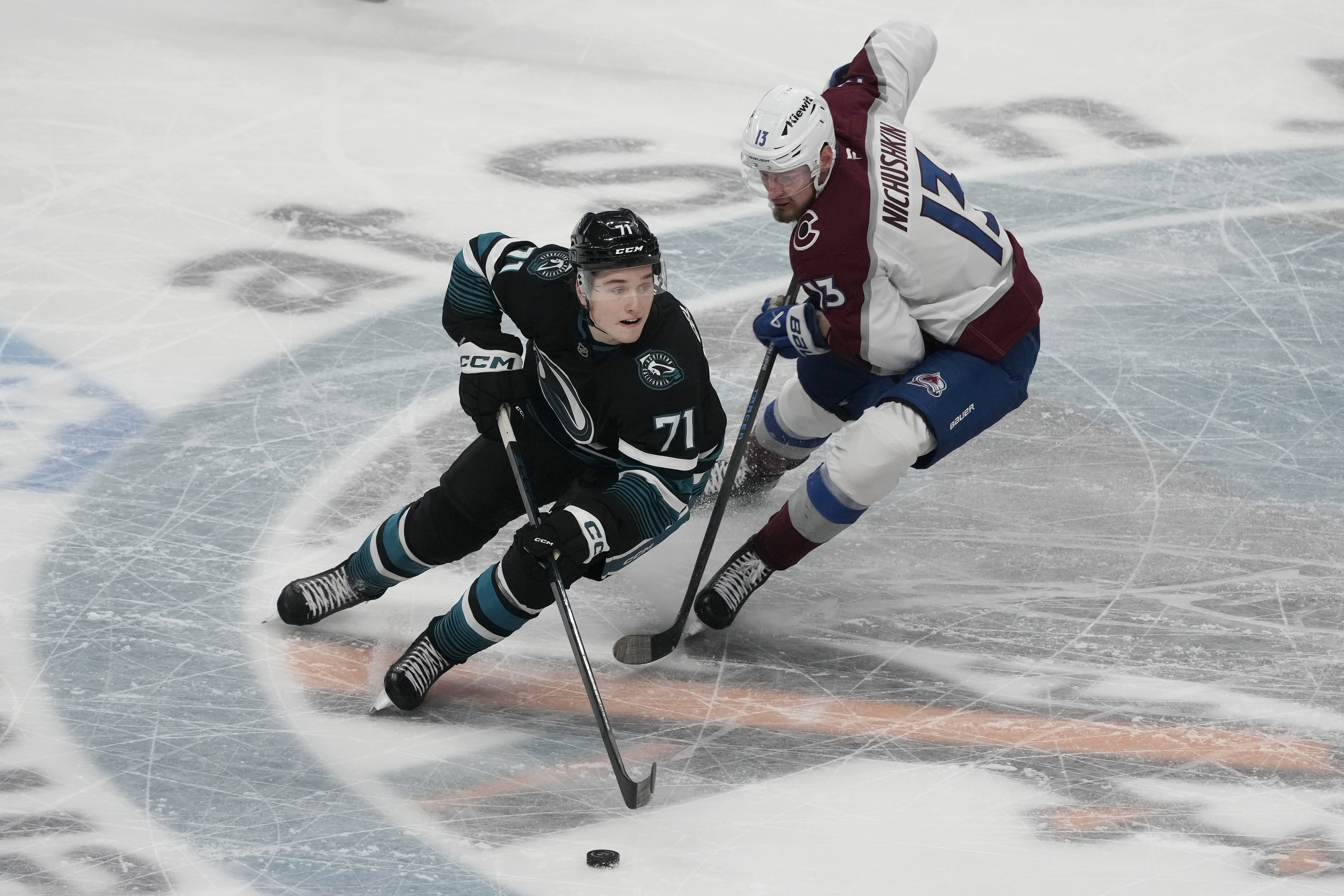 San Jose Sharks center Macklin Celebrini (71) skates with the puck against Colorado Avalanche right wing Valeri Nichushkin (13) during the third period of an NHL hockey game in San Jose, Calif., Thursday, Dec. 19, 2024.