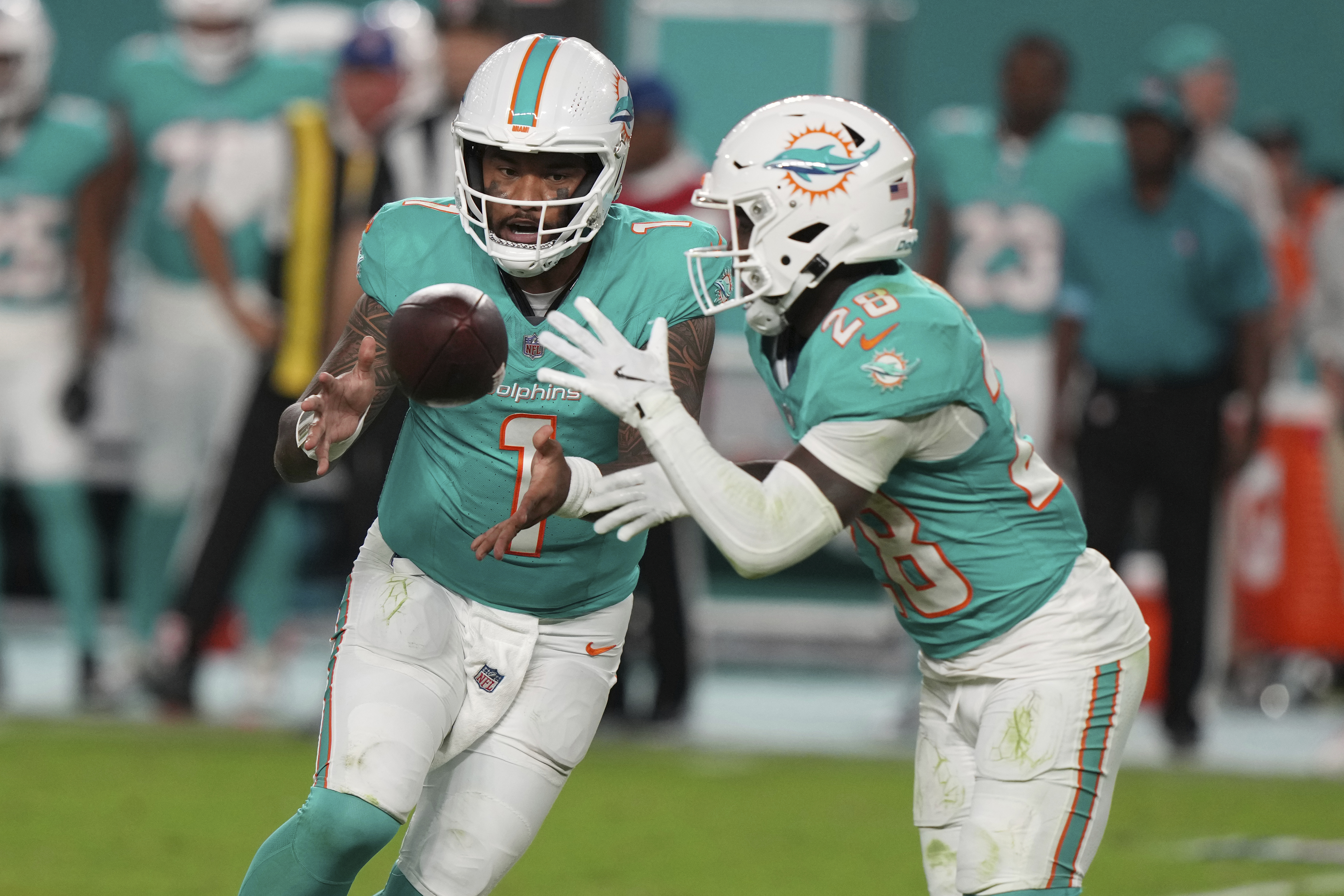 Miami Dolphins quarterback Tua Tagovailoa (1) pitches the football to Miami Dolphins running back De'Von Achane (28) during the second half of an NFL football game against the San Francisco 49ers, Sunday, Dec. 22, 2024, in Miami Gardens, Fla.