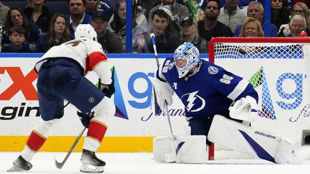 Florida Panthers center Eetu Luostarinen, left, scores against Tampa Bay Lightning goaltender Andrei Vasilevskiy (88) during the second period of an NHL hockey game Sunday, Dec. 22, 2024, in Tampa, Fla.