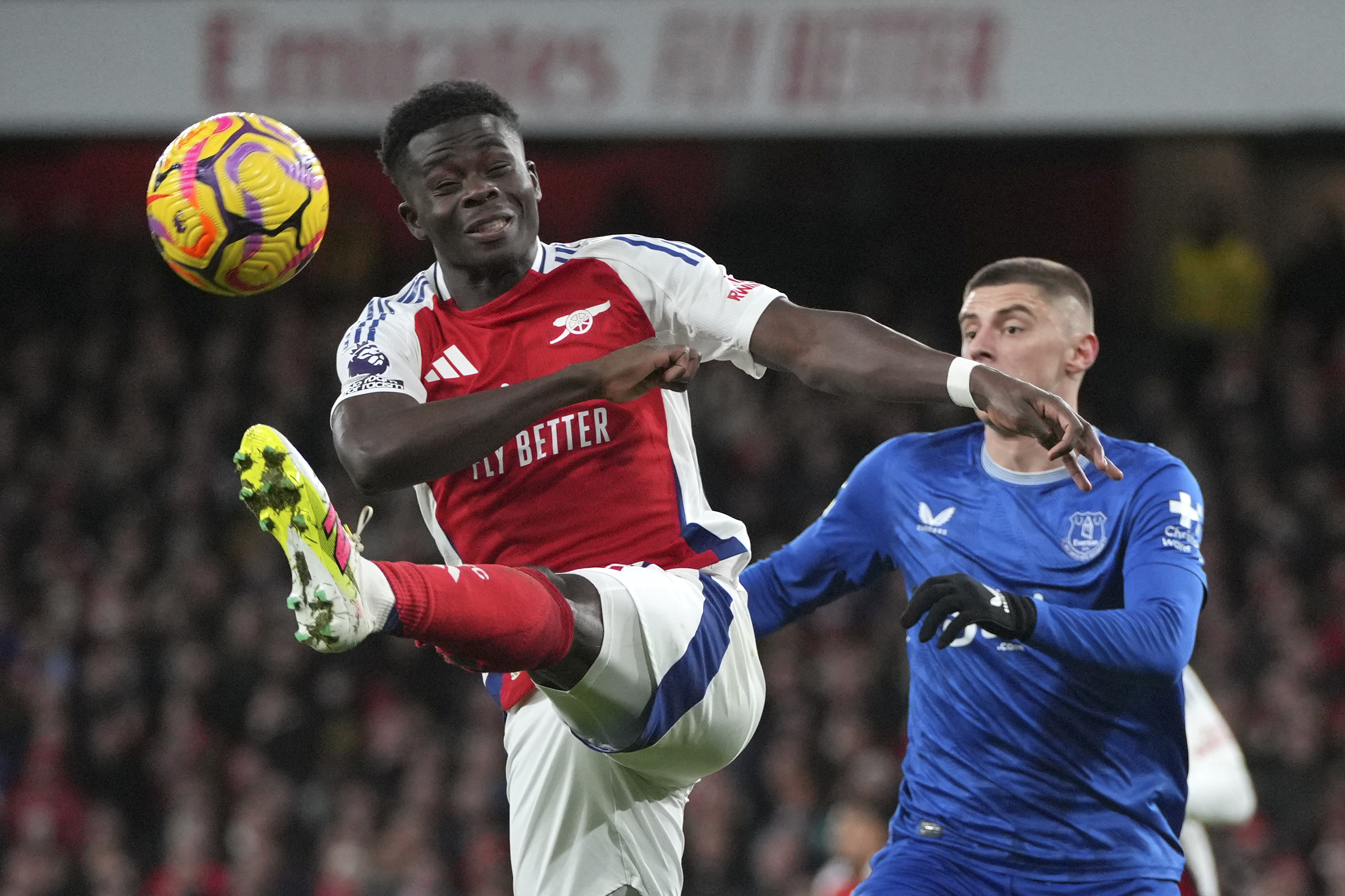 Arsenal's Bukayo Saka, left, kicks the ball ahead of Everton's Vitaliy Mykolenko during the English Premier League soccer match between Arsenal and Everton at Emirates Stadium in London, Saturday, Dec. 14, 2024.