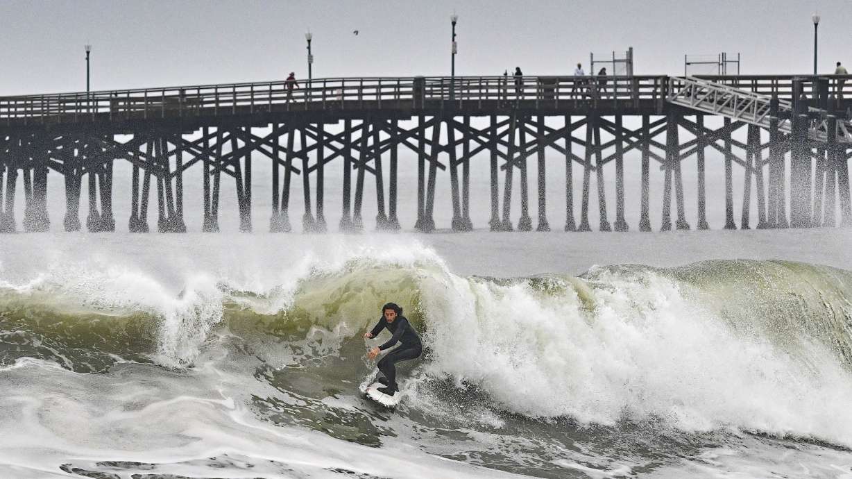 Surfers take to the water as big waves hit the shore in Seal Beach, Calif., Monday. Two people were rescued when a California pier partially collapsed.