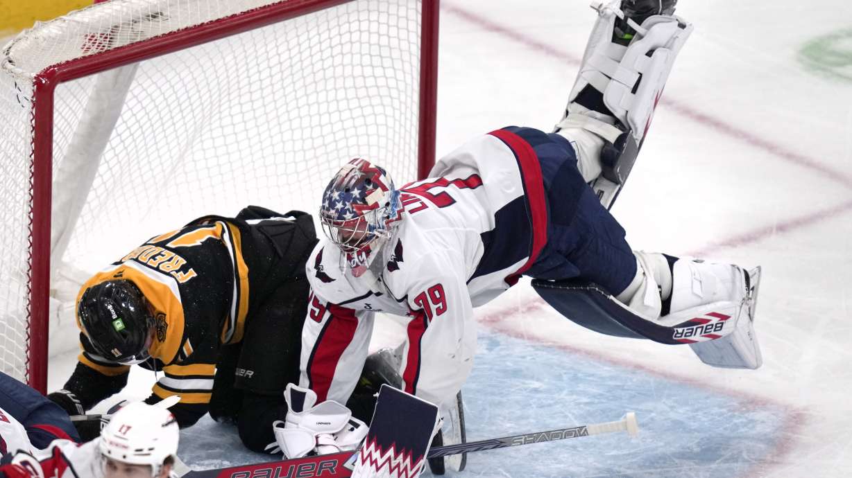 Washington Capitals goaltender Charlie Lindgren (79) goes airborne while colliding with Boston Bruins center Trent Frederic (11) during the second period of an NHL hockey game, Monday, Dec. 23, 2024, in Boston.
