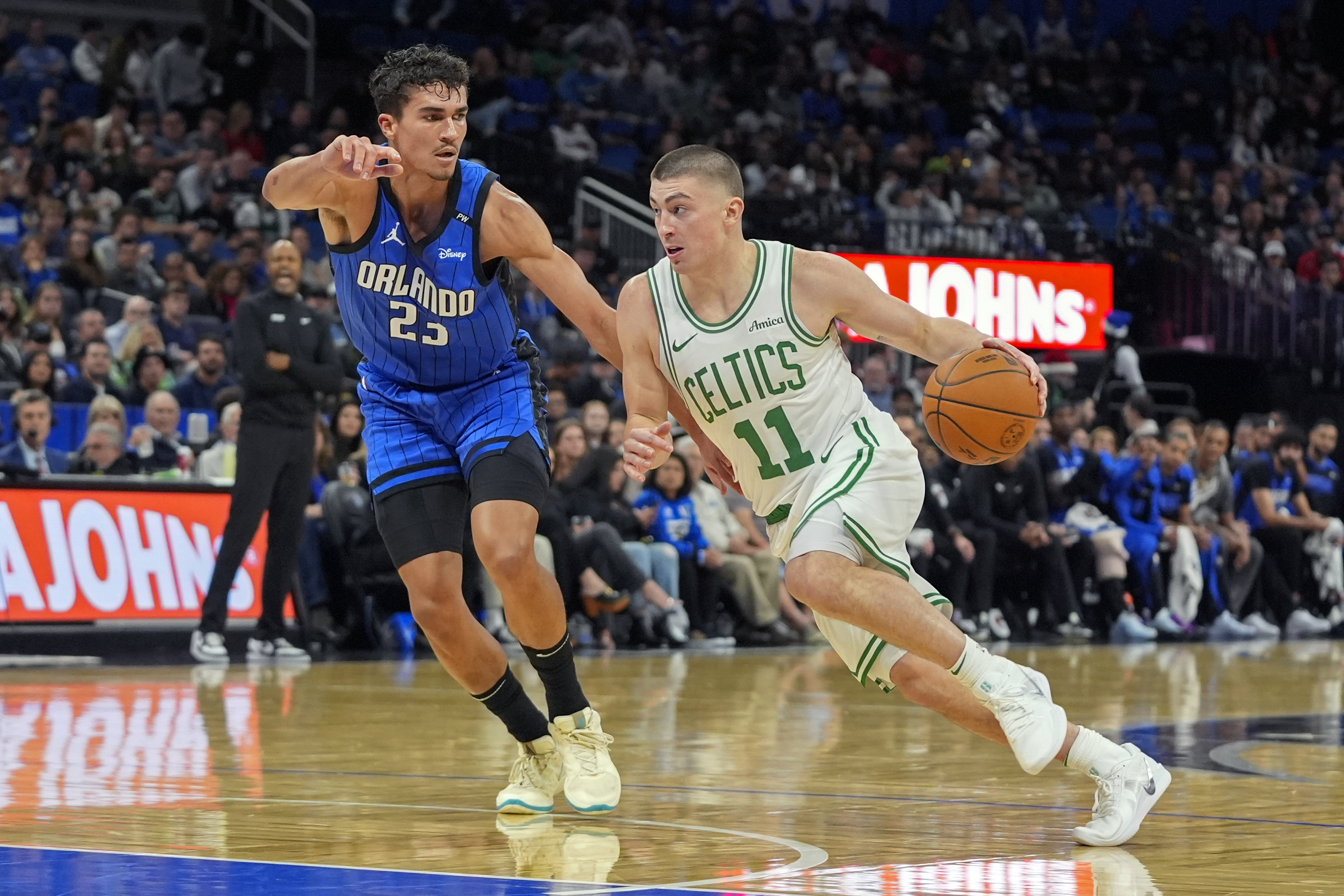 Boston Celtics guard Payton Pritchard (11) drives past Orlando Magic forward Tristan da Silva (23) during the first half of an NBA basketball game, Monday, Dec. 23, 2024, in Orlando, Fla. 