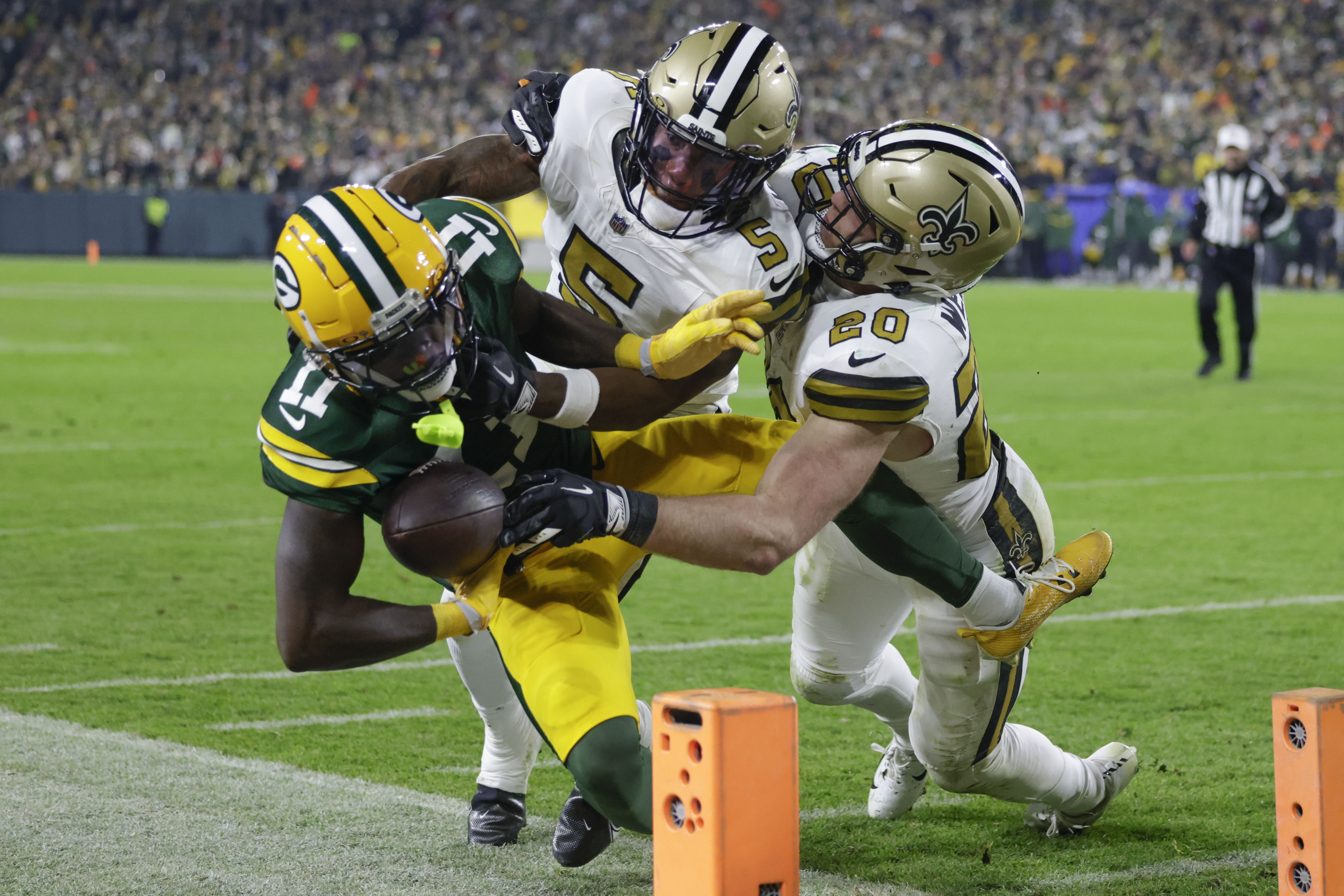 Green Bay Packers wide receiver Jayden Reed (11) is pushed out of bounds near the goal line by New Orleans Saints cornerback Will Harris (5) and linebacker Pete Werner (20) during the first half of an NFL football game, Monday, Dec. 23, 2024, in Green Bay, Wis. 