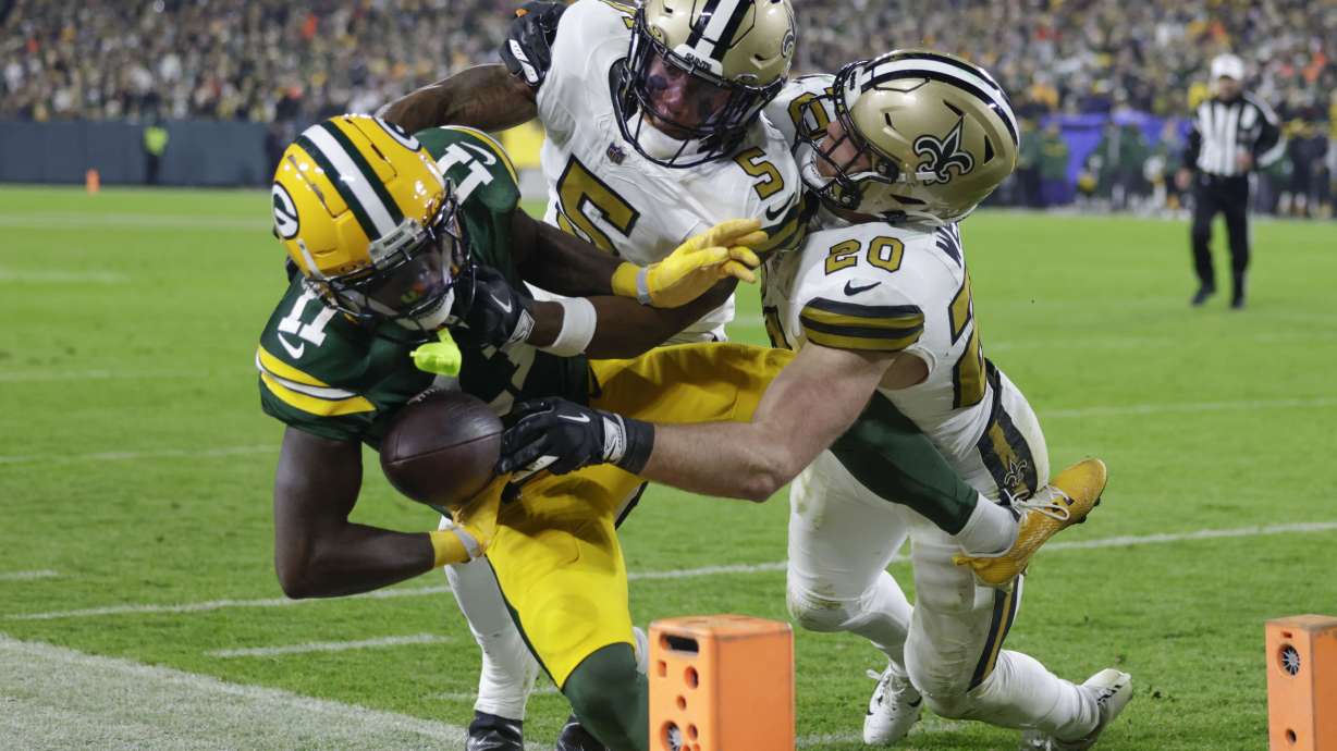 Green Bay Packers wide receiver Jayden Reed (11) is pushed out of bounds near the goal line by New Orleans Saints cornerback Will Harris (5) and linebacker Pete Werner (20) during the first half of an NFL football game, Monday, Dec. 23, 2024, in Green Bay, Wis.