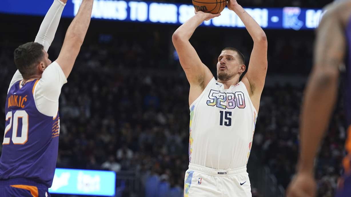 Denver Nuggets center Nikola Jokic, right, goes up for a basket as Phoenix Suns center Jusuf Nurkic defends in the first half of an NBA basketball game Monday, Dec. 23, 2024, in Denver.