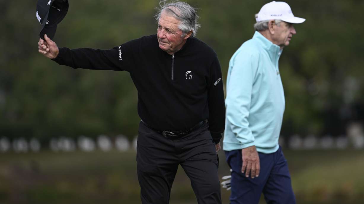 Gary Player, left, acknowledges the crowd as he and Nick Price, right, walk to the 18th green during the final round of the PNC Championship golf tournament, Sunday, Dec. 22, 2024, in Orlando, Fla.