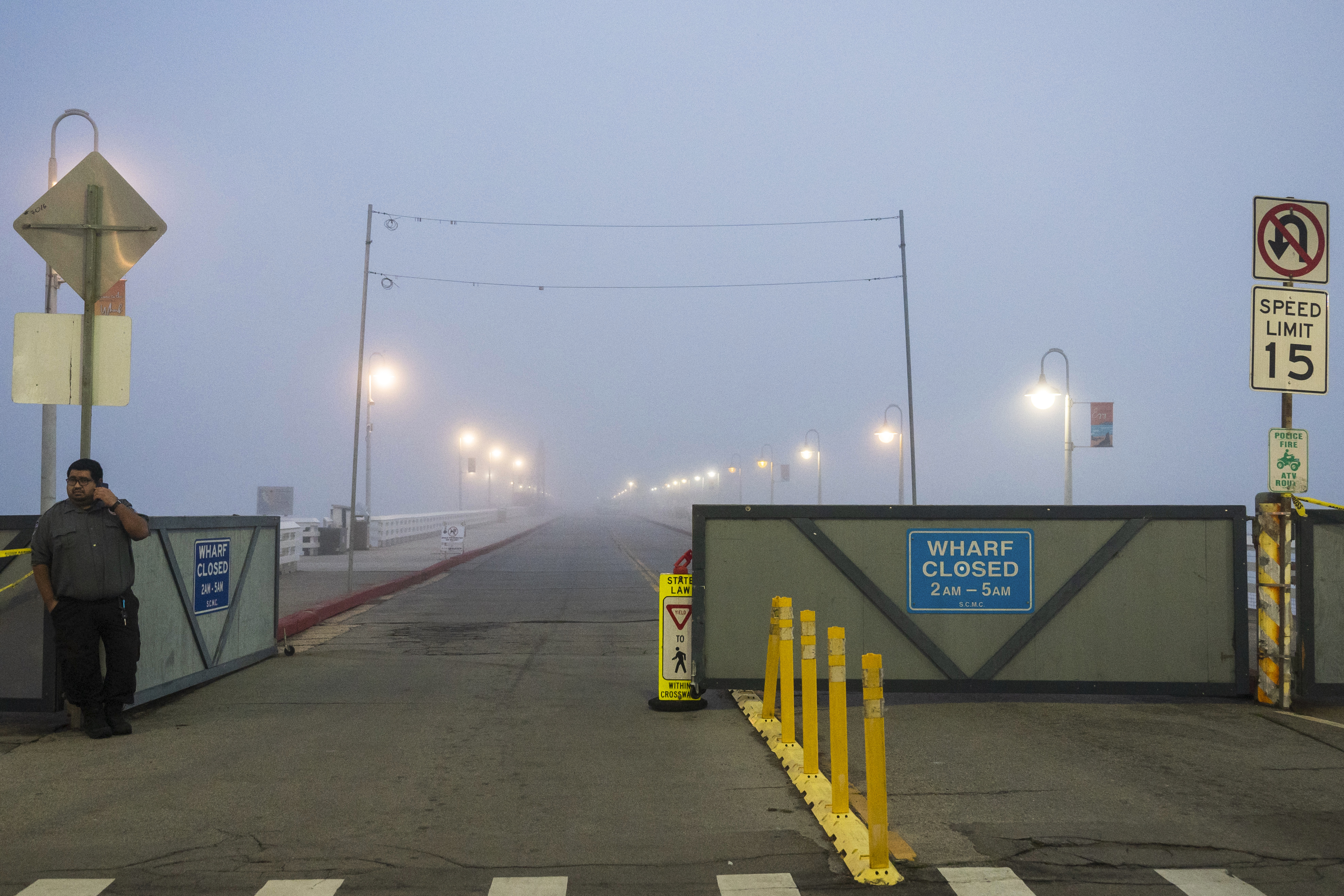 A security guard watches the entrance to the closed Santa Cruz Wharf in Santa Cruz, Calif. Monday.