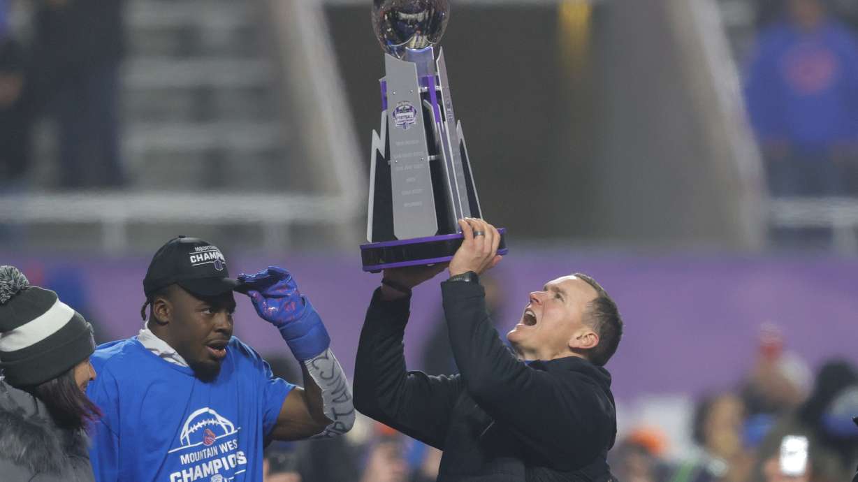 Boise State head coach Spencer Danielson celebrates with safety Seyi Oladipo, the defensive player of the game, with the Championship Trophy after their matchup against UNLV in the Mountain West Championship NCAA college football game Friday, Dec. 6, 2024, in Boise, Idaho.