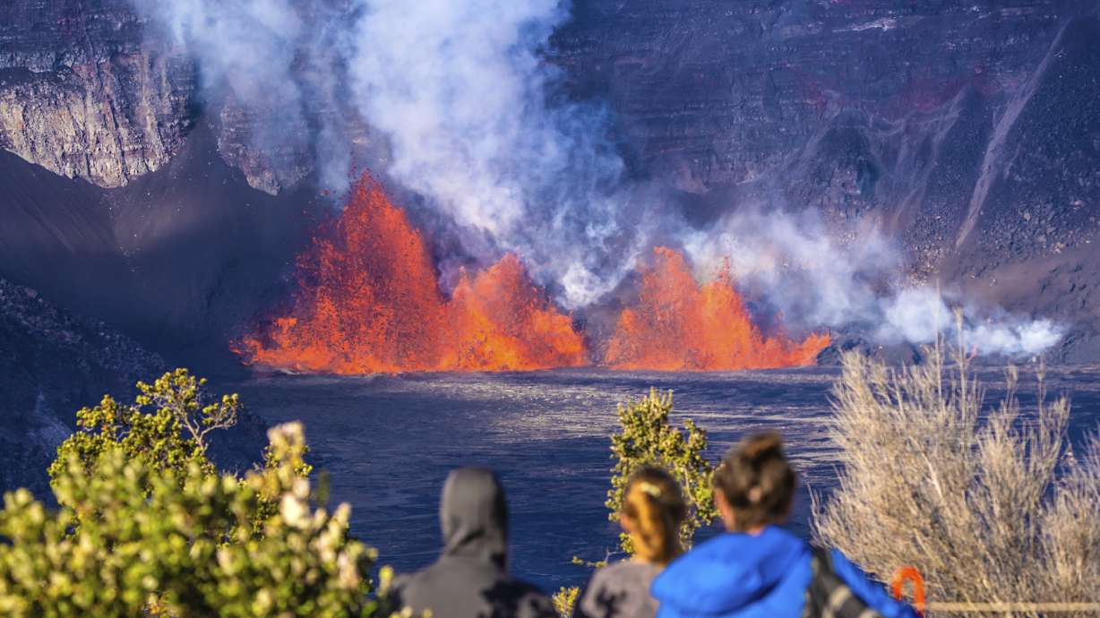 In this photo provided by the National Park Service, people watch as an eruption takes place on the summit of the Kilauea volcano in Hawaii, Monday.