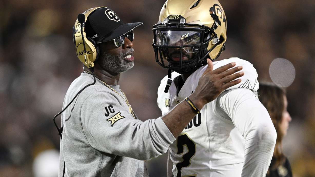 Colorado head coach Deion Sanders, left, talks with quarterback Shedeur Sanders (2) during a timeout in the second half of an NCAA college football game against Central Florida, Saturday, Sept. 28, 2024, in Orlando, Fla.