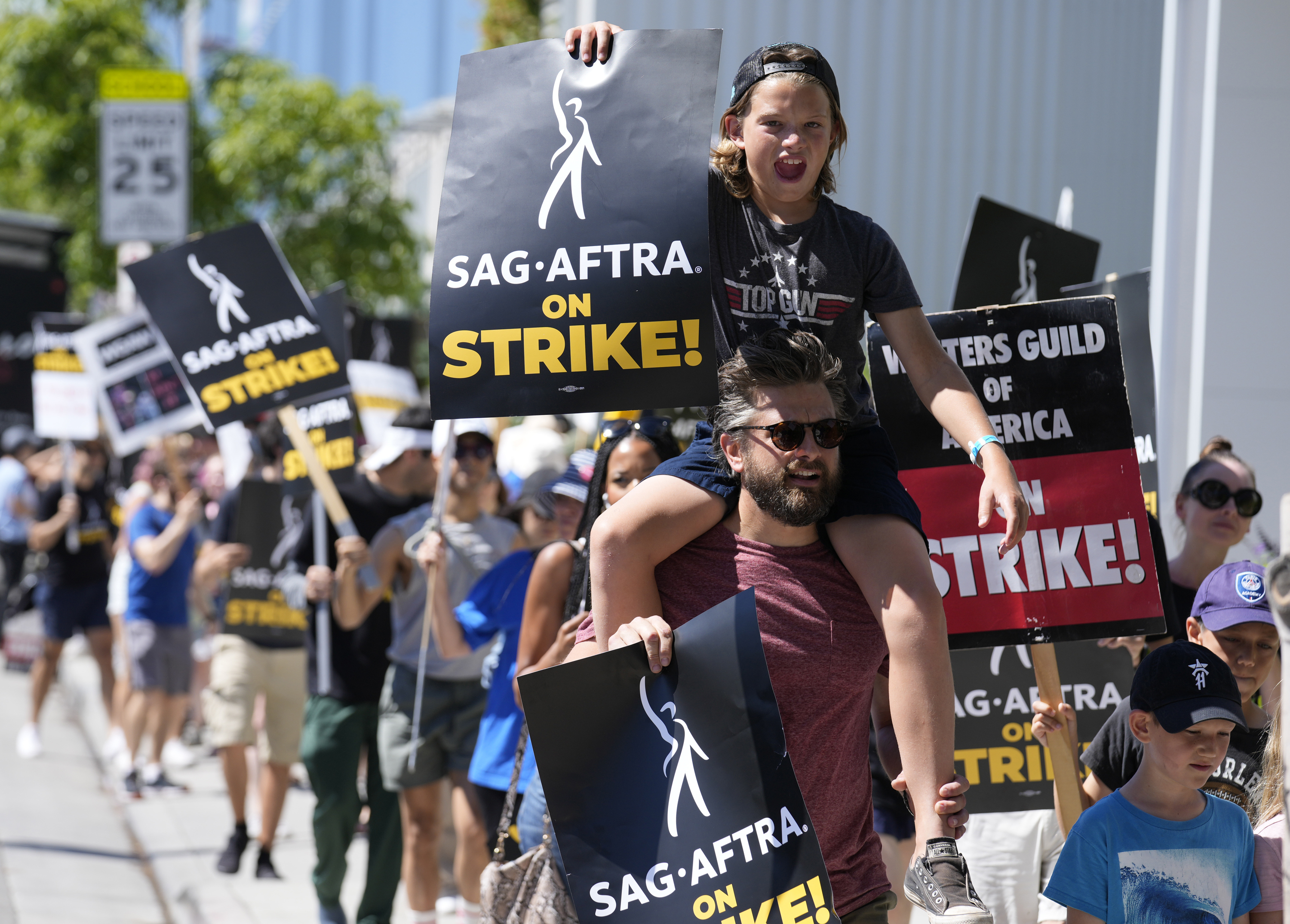 Director of Photography Jac Cheairs and his son, actor Wyatt Cheairs, 11, take part in a rally by striking writers and actors outside Netflix studio in Los Angeles on July 14, 2023.