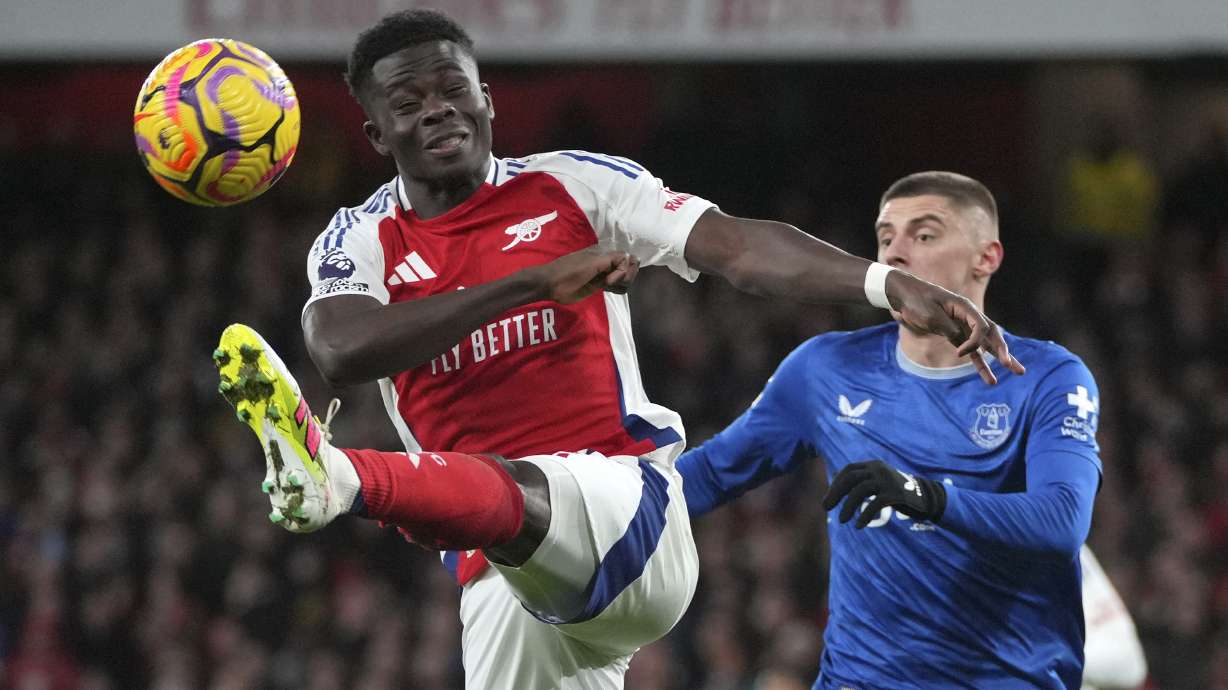 Arsenal's Bukayo Saka, left, kicks the ball ahead of Everton's Vitaliy Mykolenko during the English Premier League soccer match between Arsenal and Everton at Emirates Stadium in London, Saturday, Dec. 14, 2024.