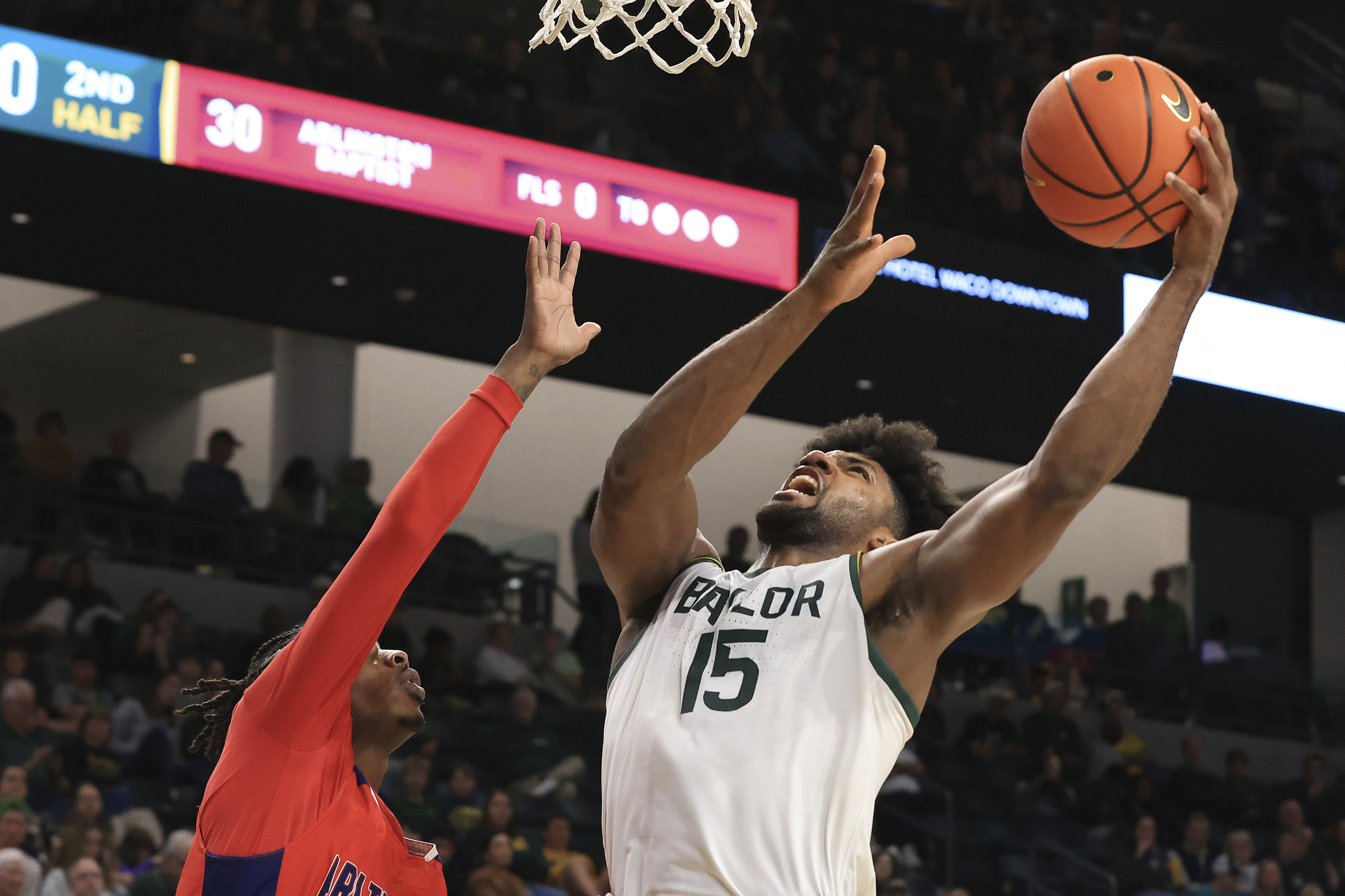 Baylor forward Norchad Omier (15) goes up to score over Arlington Baptist guard Ahmad Webster, left, during the second half of an NCAA college basketball game Friday, Dec. 27, 2024, in Waco, Texas. 