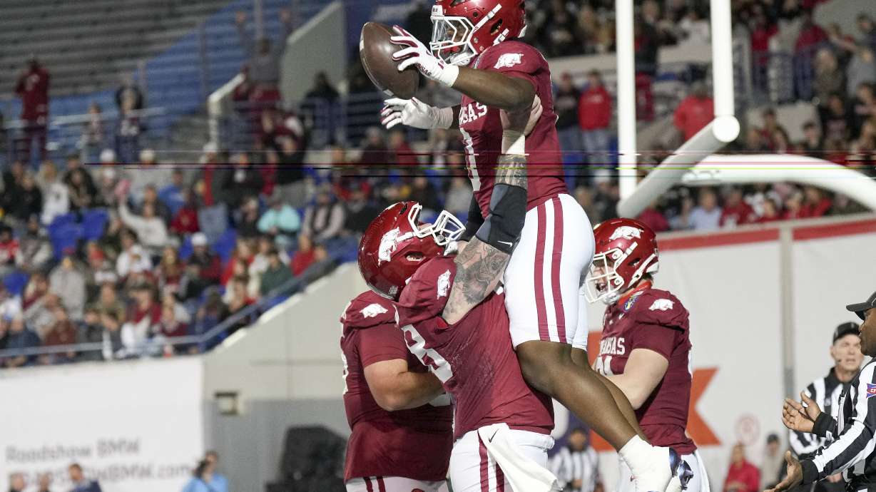 Arkansas running back Braylen Russell, top, celebrates his touchdown with a teammate during the first half of the Liberty Bowl NCAA college football game against Texas Tech, Friday, Dec. 27, 2024, in Memphis, Tenn.