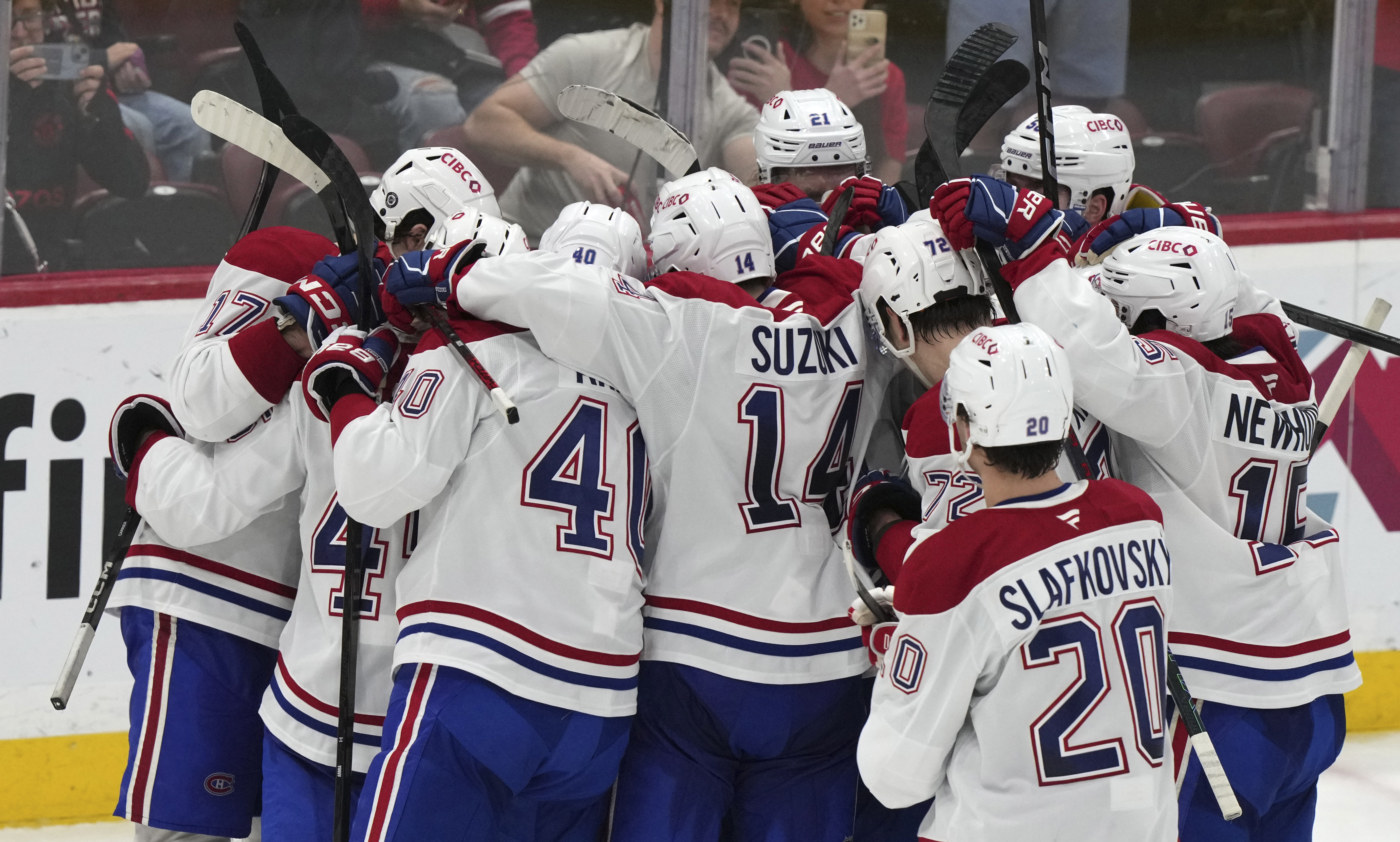 Montreal Canadiens players surround goaltender Jakub Dobes, not seen, after the Canadiens defeated the Florida Panthers 4-0 in an NHL hockey game, Saturday, Dec. 28, 2024, in Sunrise, Fla. 