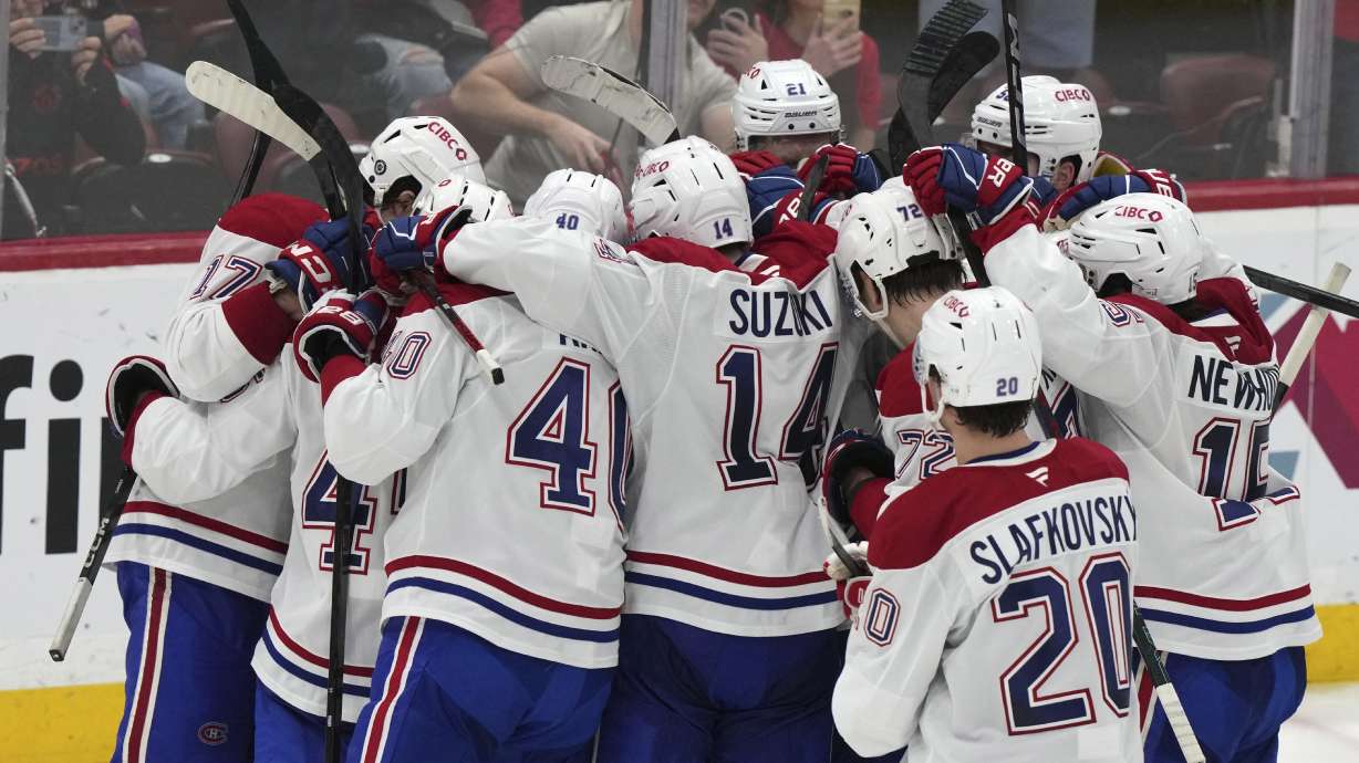Montreal Canadiens players surround goaltender Jakub Dobes, not seen, after the Canadiens defeated the Florida Panthers 4-0 in an NHL hockey game, Saturday, Dec. 28, 2024, in Sunrise, Fla.