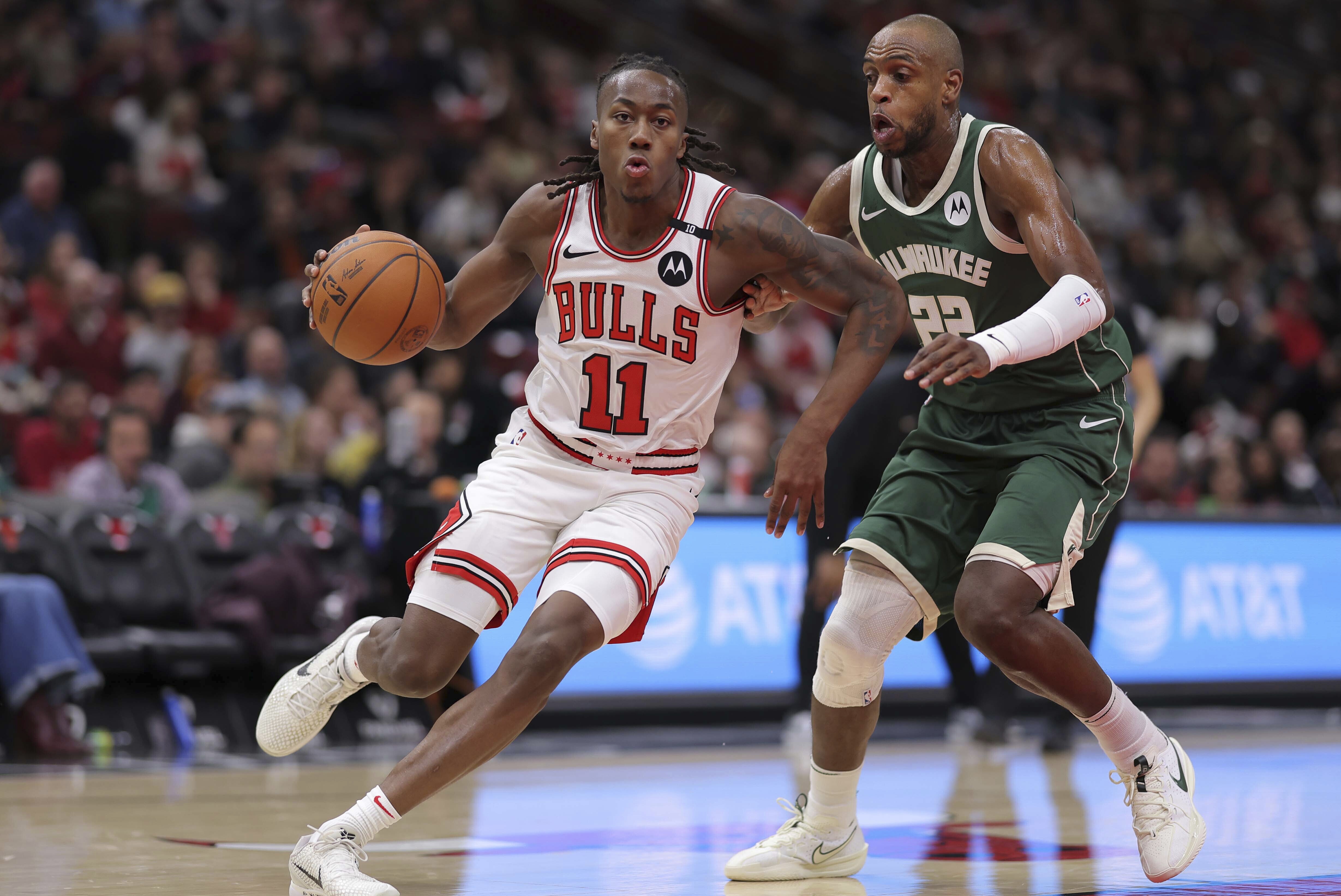 Chicago Bulls guard Ayo Dosunmu (11) left, drives to the basket past Milwaukee Bucks forward Khris Middleton during the second half of an NBA basketball game, Monday, Dec. 23, 2024, in Chicago.