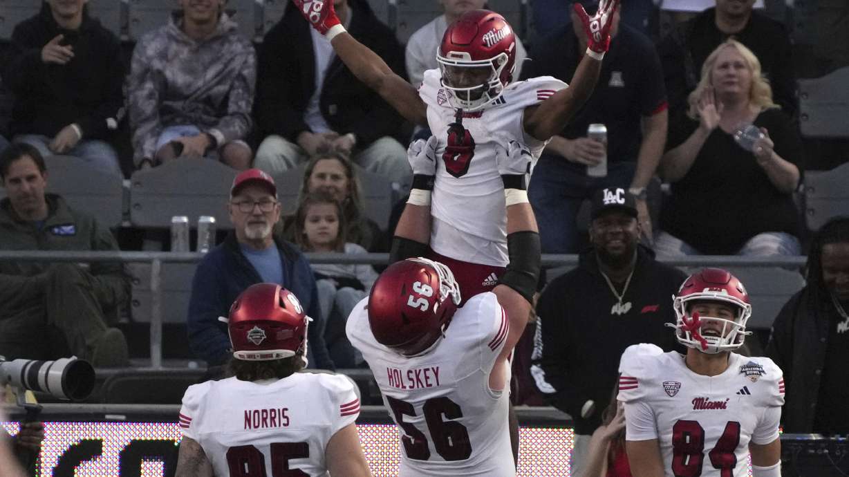 Miami (Ohio) running back Kevin Davis (8) is lifted by offensive lineman Reid Holskey (56) after scoring a touchdown against Colorado State in the second half of the Arizona Bowl NCAA college football game, Saturday, Dec. 28, 2024, in Tucson, Ariz.