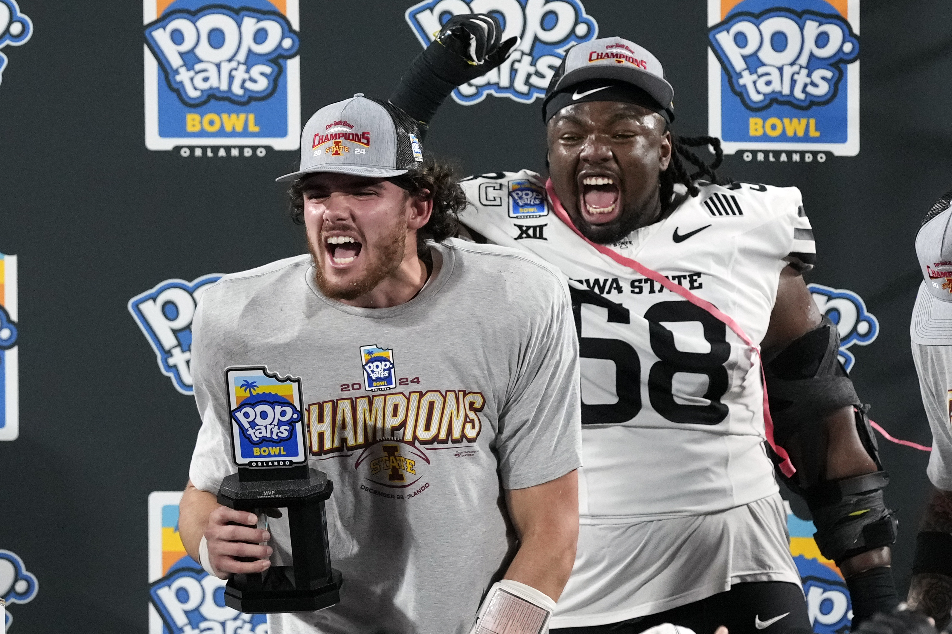 MVP Iowa State quarterback Rocco Becht, left, celebrates with his trophy as teammate defensive lineman J.R. Singleton (58) cheers after Iowa State defeated Miami in the Pop Tarts Bowl NCAA college football game, Saturday, Dec. 28, 2024, in Orlando, Fla. 