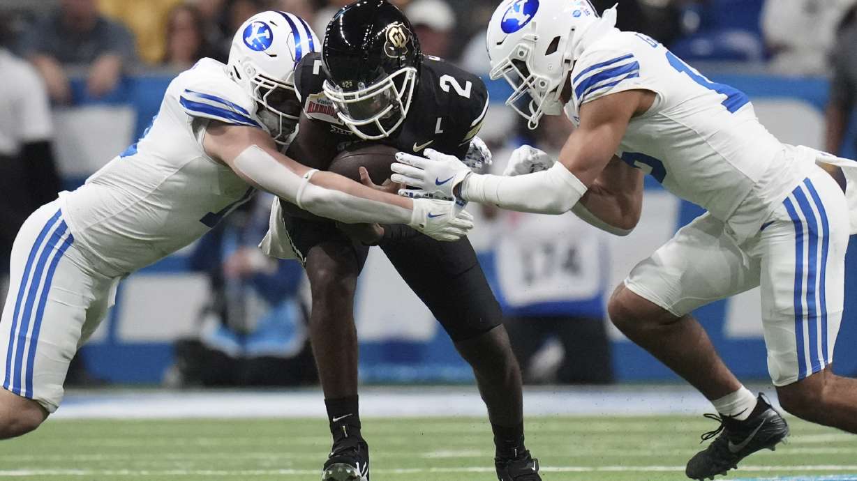 Colorado quarterback Shedeur Sanders (2) is hit by BYU linebackers Harrison Taggart, left, and Isaiah Glasker, right, during the first half of the Alamo Bowl NCAA college football game, Saturday, Dec. 28, 2024, in San Antonio.