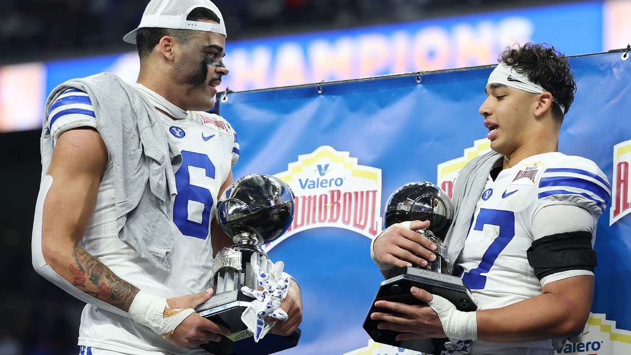 Brigham Young linebacker Isaiah Glasker (16) and BYU running back LJ Martin hold their defense and offensive trophies during the Valero Alamo Bowl in San Antonio on Saturday, Dec. 28, 2024. BYU won 36-14.