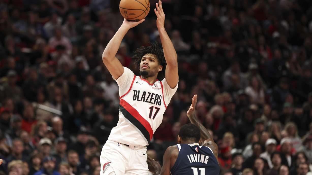 Portland Trail Blazers guard Shaedon Sharpe (17) shoots from beside Dallas Mavericks guard Kyrie Irving (11) during the second half of an NBA basketball game Saturday, Dec. 28, 2024, in Portland, Ore.
