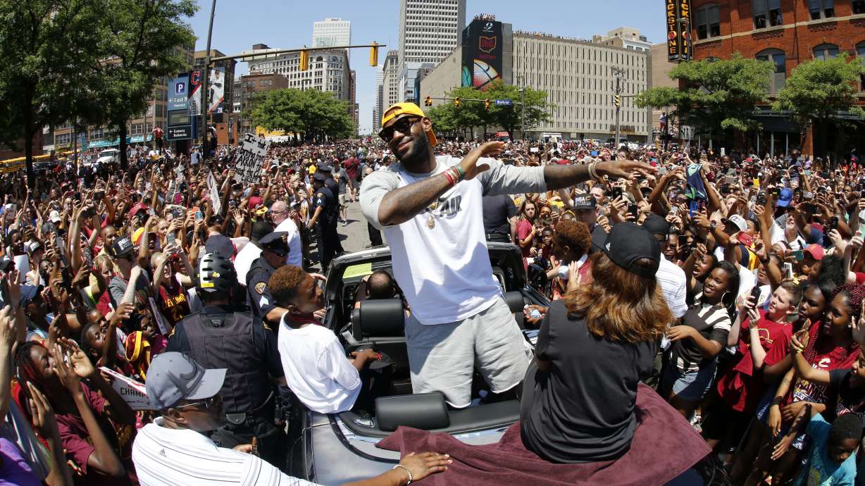 FILE - Cleveland Cavaliers' LeBron James, center, stands in the back of a Rolls Royce as it makes its way through the crowd lining the parade route in downtown Cleveland, on June 22, 2016, celebrating the basketball team's NBA championship.