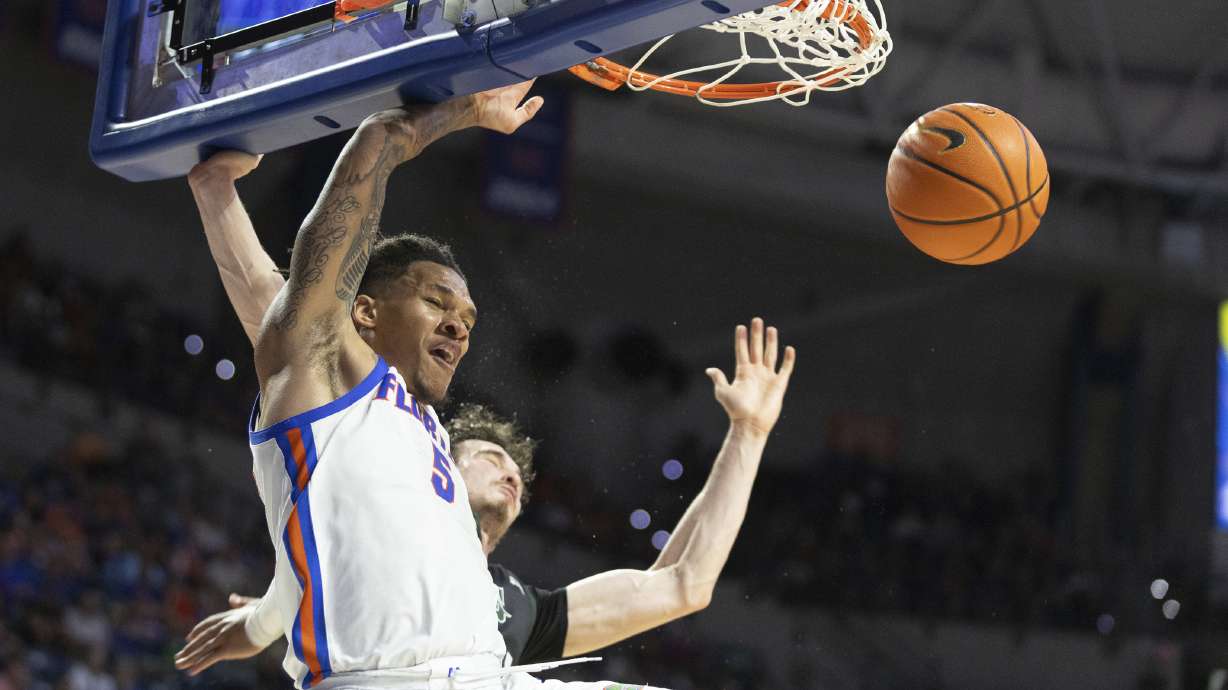 Florida guard Will Richard (5) dunks under pressure from Stetson forward Jordan Wood, right, during the first half of an NCAA college basketball game Sunday, Dec. 29, 2024, in Gainesville, Fla.