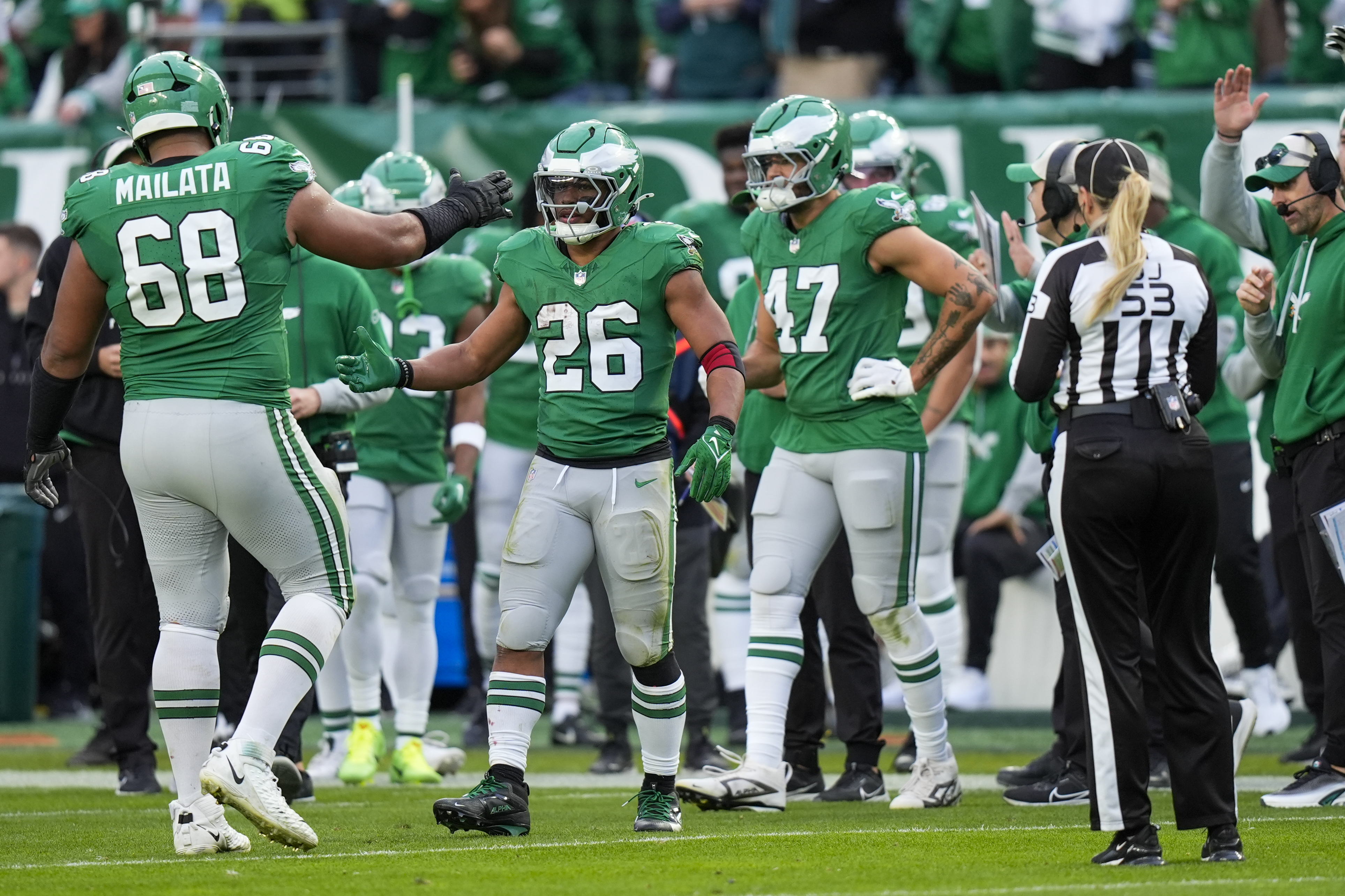 Philadelphia Eagles running back Saquon Barkley (26) is congratulated by offensive tackle Jordan Mailata and teammates after running for a long gain to put him at over 2,000 yards for the season during the second half of an NFL football game against the Dallas Cowboys, Sunday, Dec. 29, 2024, in Philadelphia.