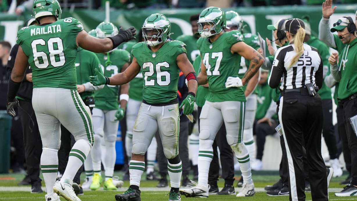 Philadelphia Eagles running back Saquon Barkley (26) is congratulated by offensive tackle Jordan Mailata and teammates after running for a long gain to put him at over 2,000 yards for the season during the second half of an NFL football game against the Dallas Cowboys, Sunday, Dec. 29, 2024, in Philadelphia.