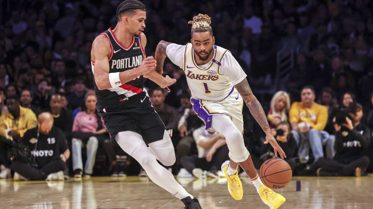Los Angeles Lakers guard D'Angelo Russell, right, dribbles past Portland Trail Blazers forward Toumani Camara, left, during the first half of an NBA basketball game, Sunday, Dec. 8, 2024, in Los Angeles.
