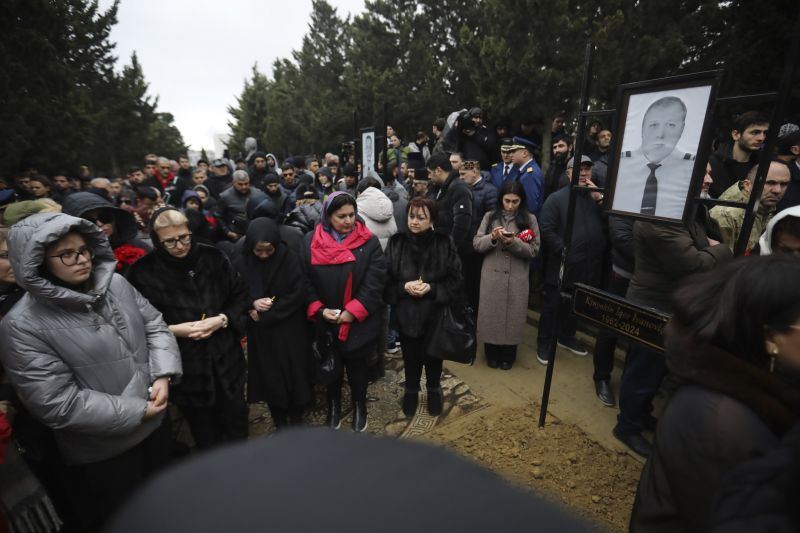 People stand at the grave of pilot in command Igor Kshnyakin during a funeral of the crew members of the Azerbaijan Airlines Embraer 190, killed in a deadly plane crash in Kazakhstan this week, at the II Alley of Honor in Baku, Azerbaijan, Sunday.