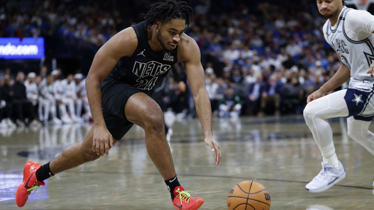 Brooklyn Nets guard Cam Thomas (24) and Orlando Magic guard Jett Howard, right, go after the ball during the first half of an NBA basketball game, Sunday, Dec. 29, 2024, in Orlando, Fla.