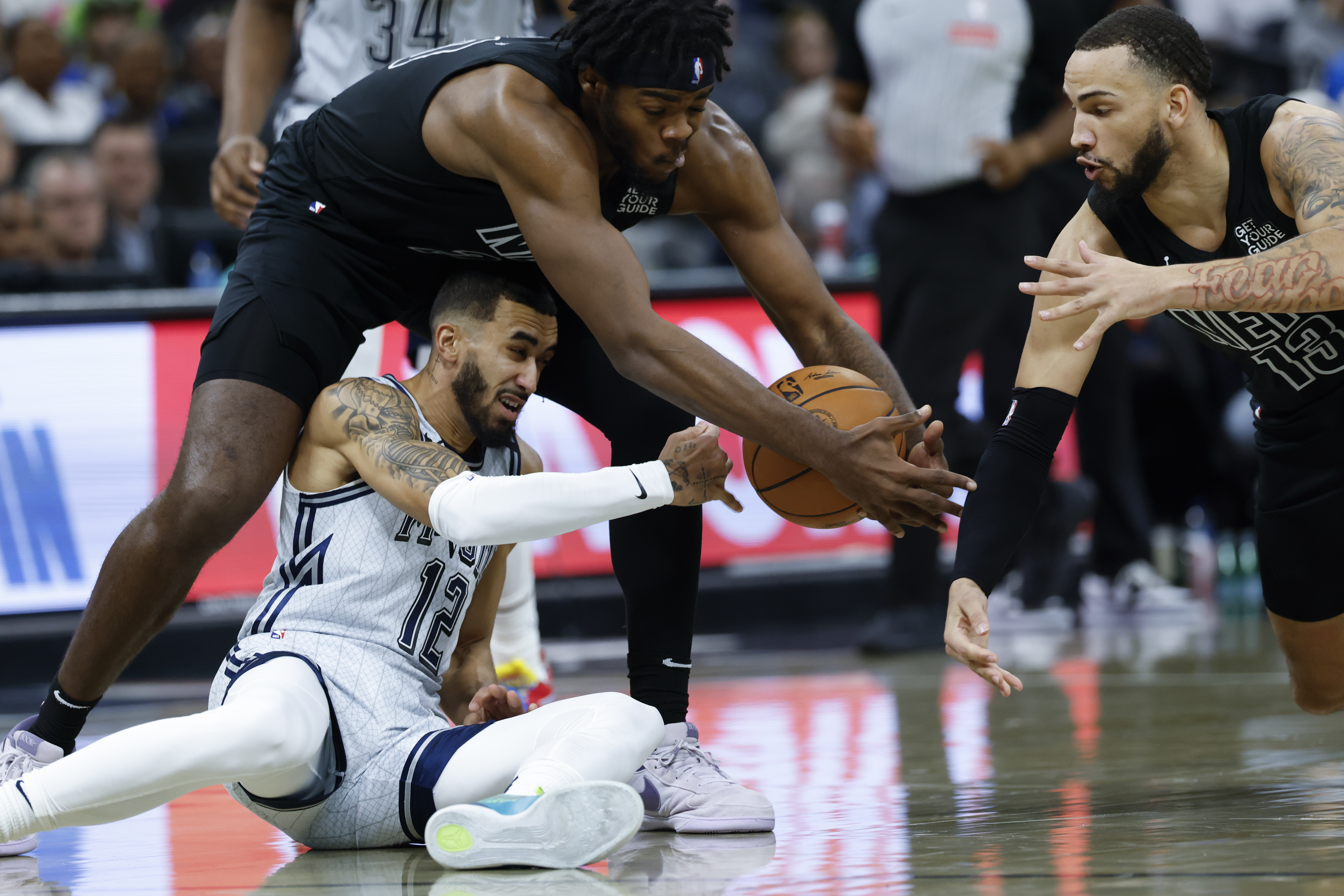 Brooklyn Nets center Day'Ron Sharpe, top left, and guard Tyrese Martin, right, go for the ball against Orlando Magic guard Trevelin Queen (12) during the first half of an NBA basketball game, Sunday, Dec. 29, 2024, in Orlando, Fla.