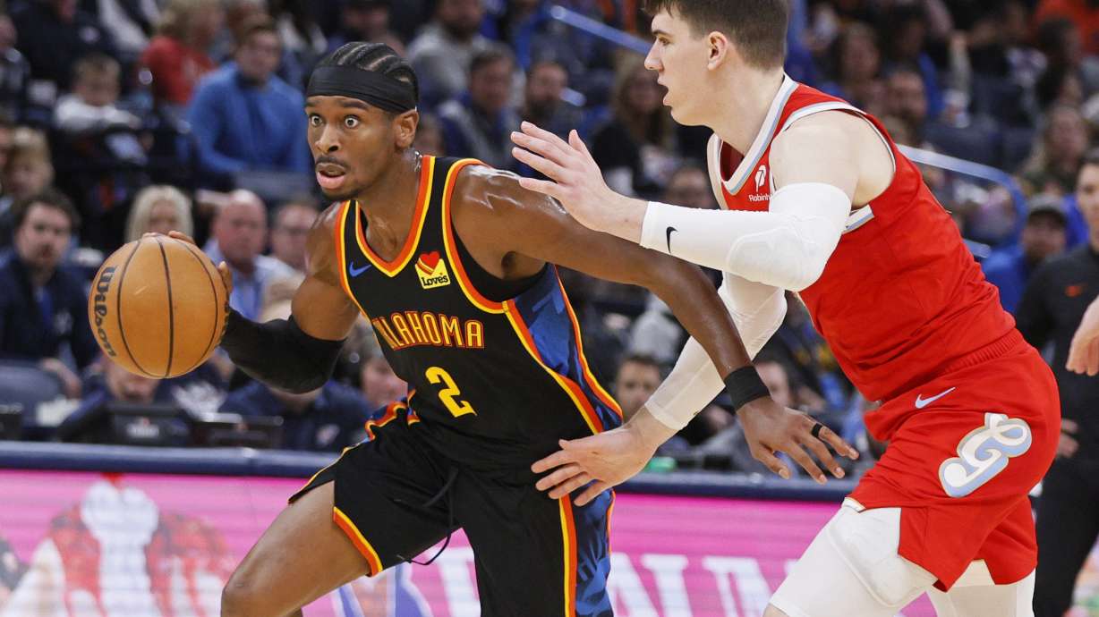 Oklahoma City Thunder guard Shai Gilgeous-Alexander (2) drives past Memphis Grizzlies forward Jake LaRavia, right, during the first half of an NBA basketball game Sunday, Dec. 29, 2024, in Oklahoma City.