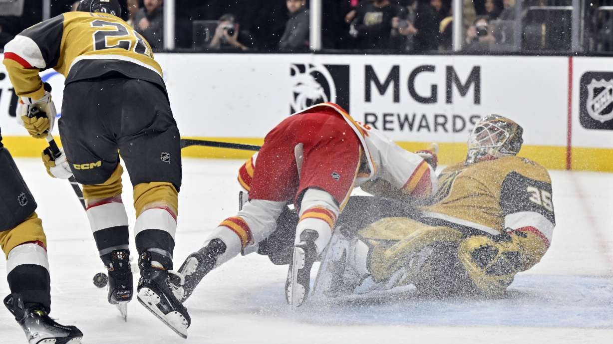 Calgary Flames left wing Ryan Lomberg, center, collides with Vegas Golden Knights goaltender Ilya Samsonov during the third period of an NHL hockey game, Sunday, Dec. 29, 2024, in Las Vegas. Lomberg was called for interference.