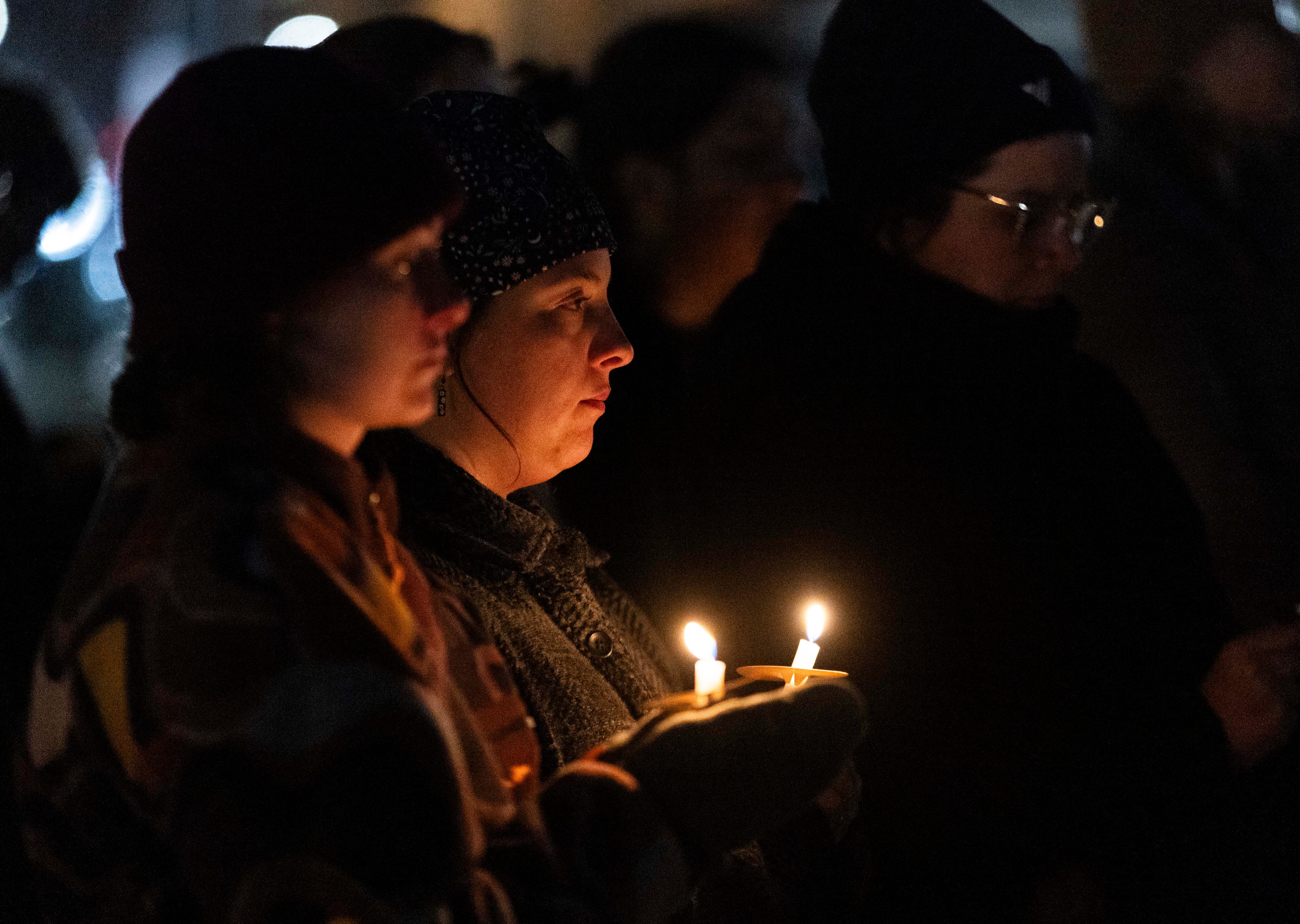 Isa Empey, left, and Haley Kline, center, both hold vigil candles while listening to a prayer during the annual Homeless Persons’ Memorial Vigil, hosted by the Salt Lake Valley Coalition to End Homelessness, in Pioneer Park in Salt Lake City on Dec. 19.