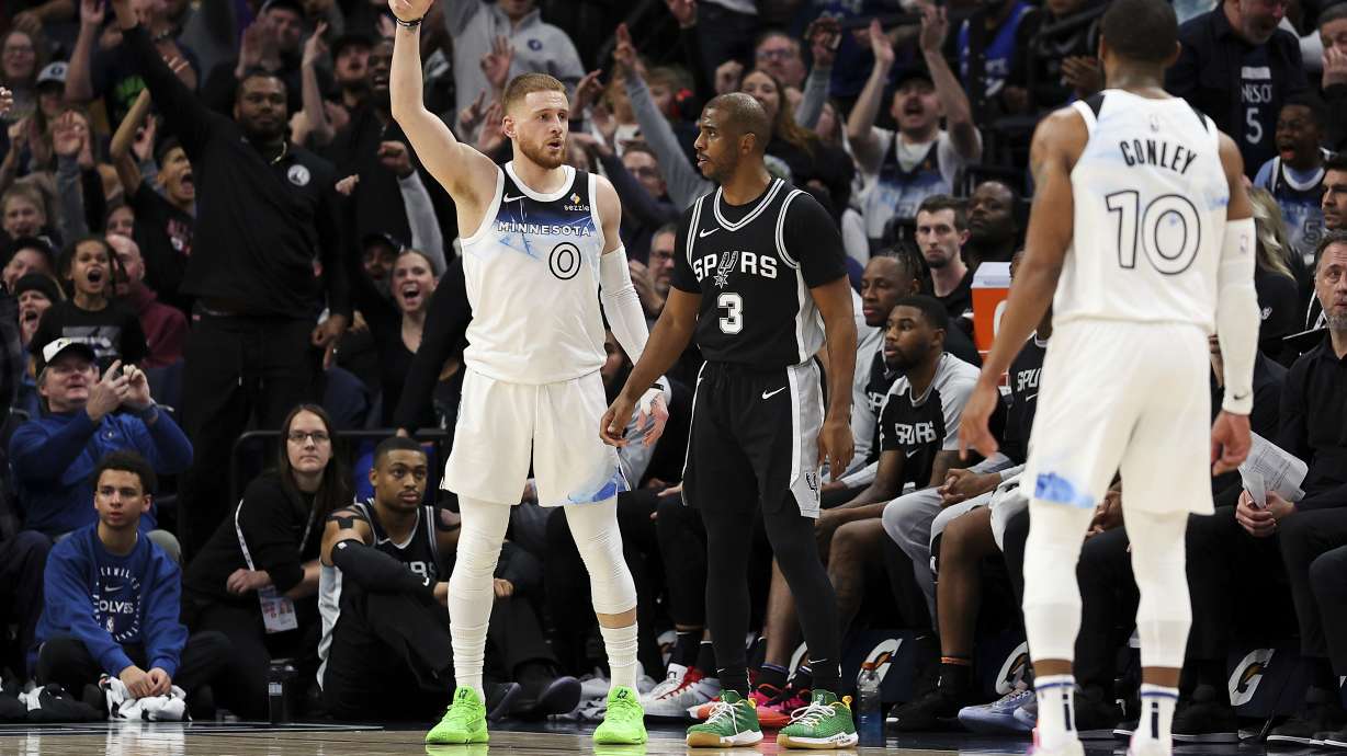Minnesota Timberwolves guard Donte DiVincenzo, left, celebrates his three-point basket as San Antonio Spurs guard Chris Paul (3) looks on during the first half of an NBA basketball game Sunday, Dec. 29, 2024, in Minneapolis.
