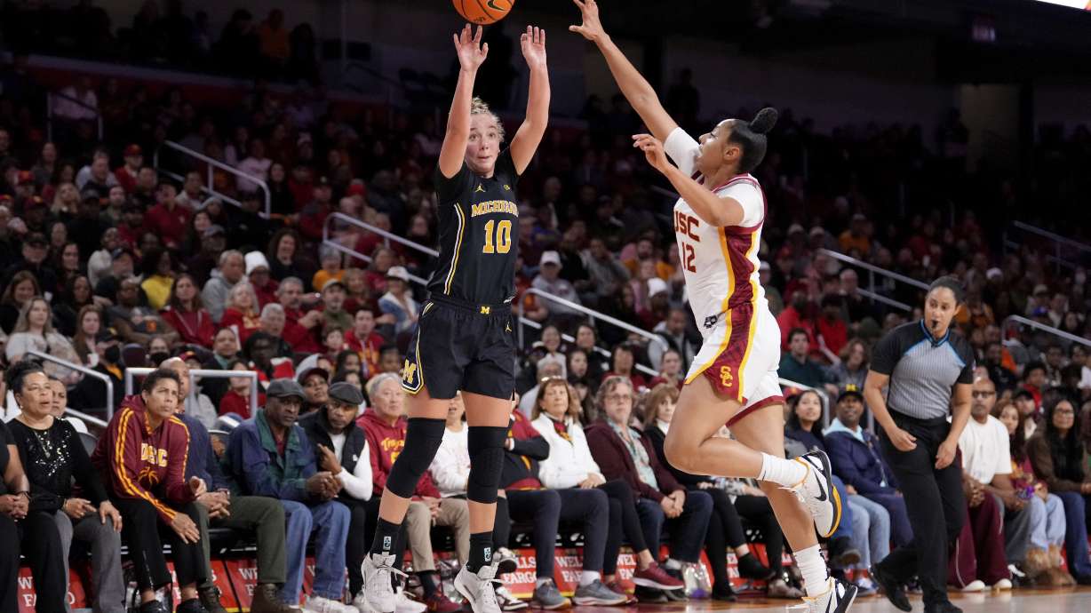 Michigan guard Jordan Hobbs, left, shoots as Southern California guard JuJu Watkins defends during the first half of an NCAA college basketball game, Sunday, Dec. 29, 2024, in Los Angeles.
