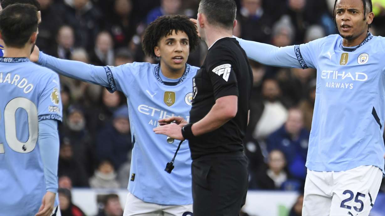 Referee Michael Oliver, center, discusses with Manchester City's Rico Lewis, second left, and Manchester City's Manuel Akanji, right, during the English Premier League soccer match between Leicester City and Manchester City at King Power stadium in Leicester, England, Sunday, Dec. 29, 2024.