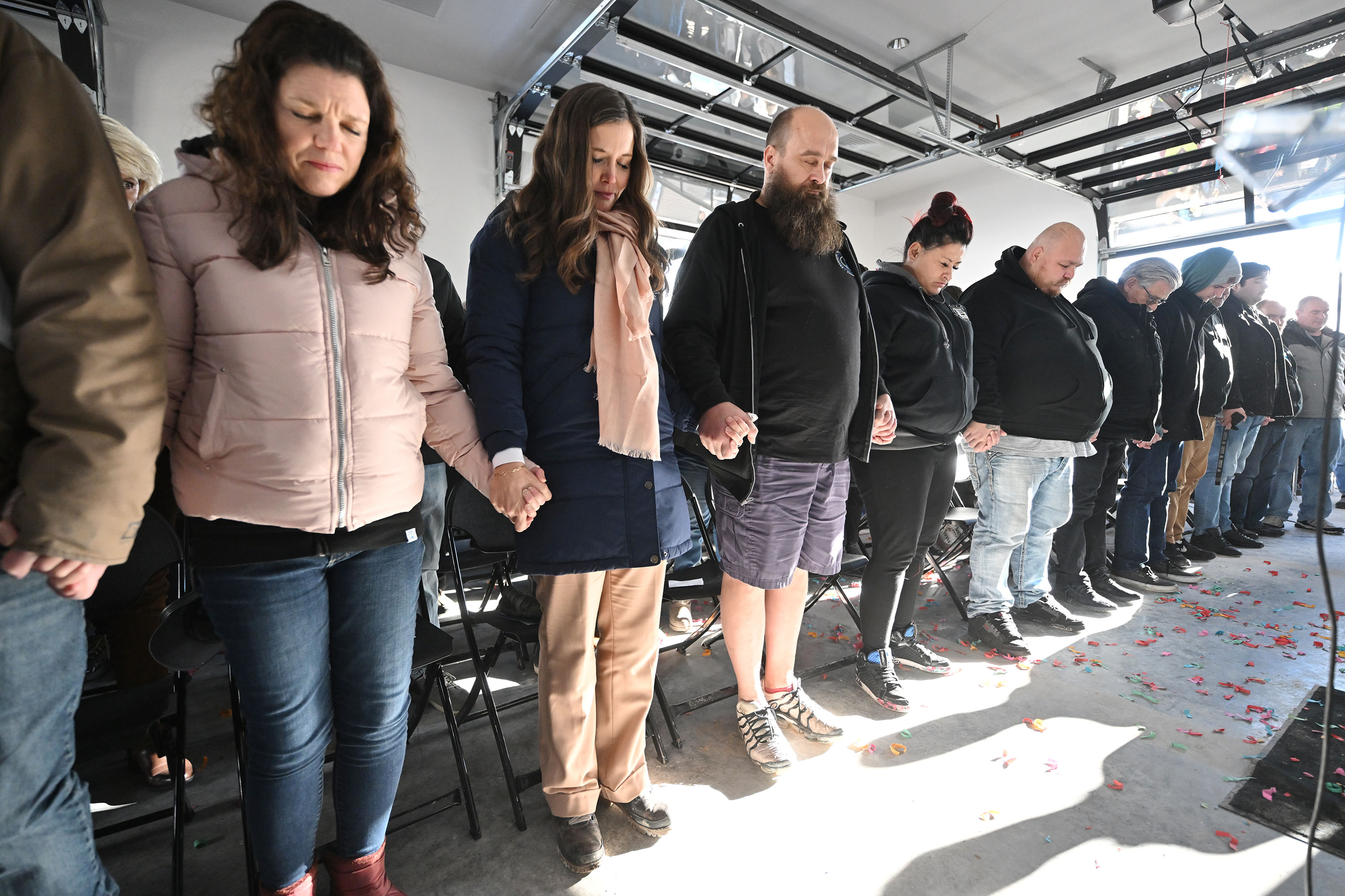 Salt Lake City Mayor Erin Mendenhall holds hands with residents Jennifer Davis and Gideon Nieman as the crowd stands and joins hands during a prayer as The Other Side Academy celebrates the grand opening of The Other Side Village on Monday.