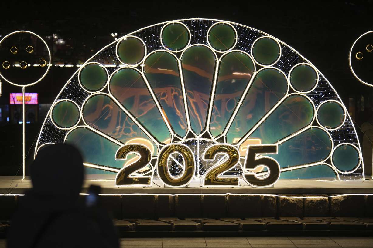 A woman holds her smartphone near an illuminated decoration on New Year's Eve in Seoul, South Korea, Tuesday.