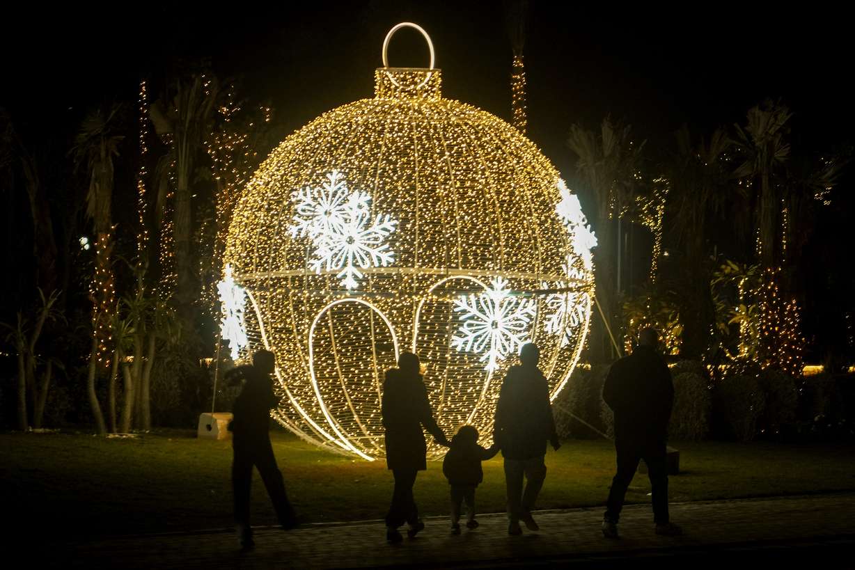 Egyptians walk in front of New Year decorations in Cairo, Egypt, Tuesday.