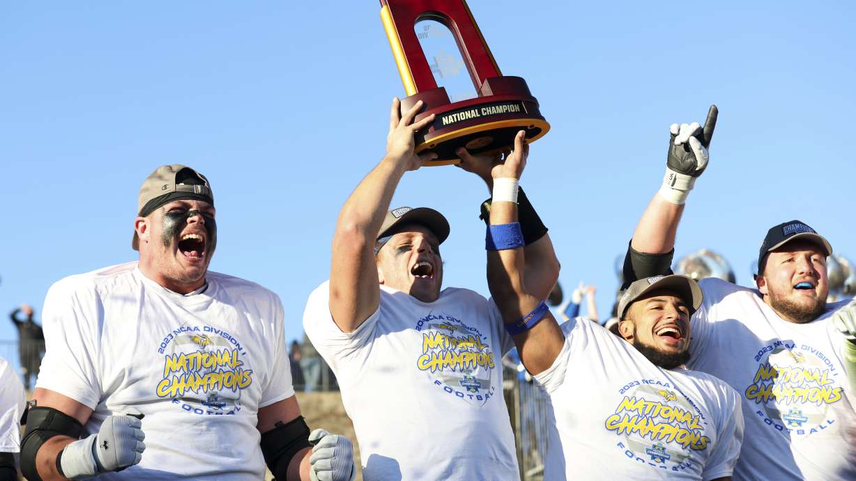 FILE- From left to right, South Dakota State's Garret Greenfield, quarterback Mark Gronowski, Jason Freeman, and Mason McCormick celebrate with the trophy after the win over Montana at the FCS Championship game, Jan. 7, 2024, in Frisco,Texas.