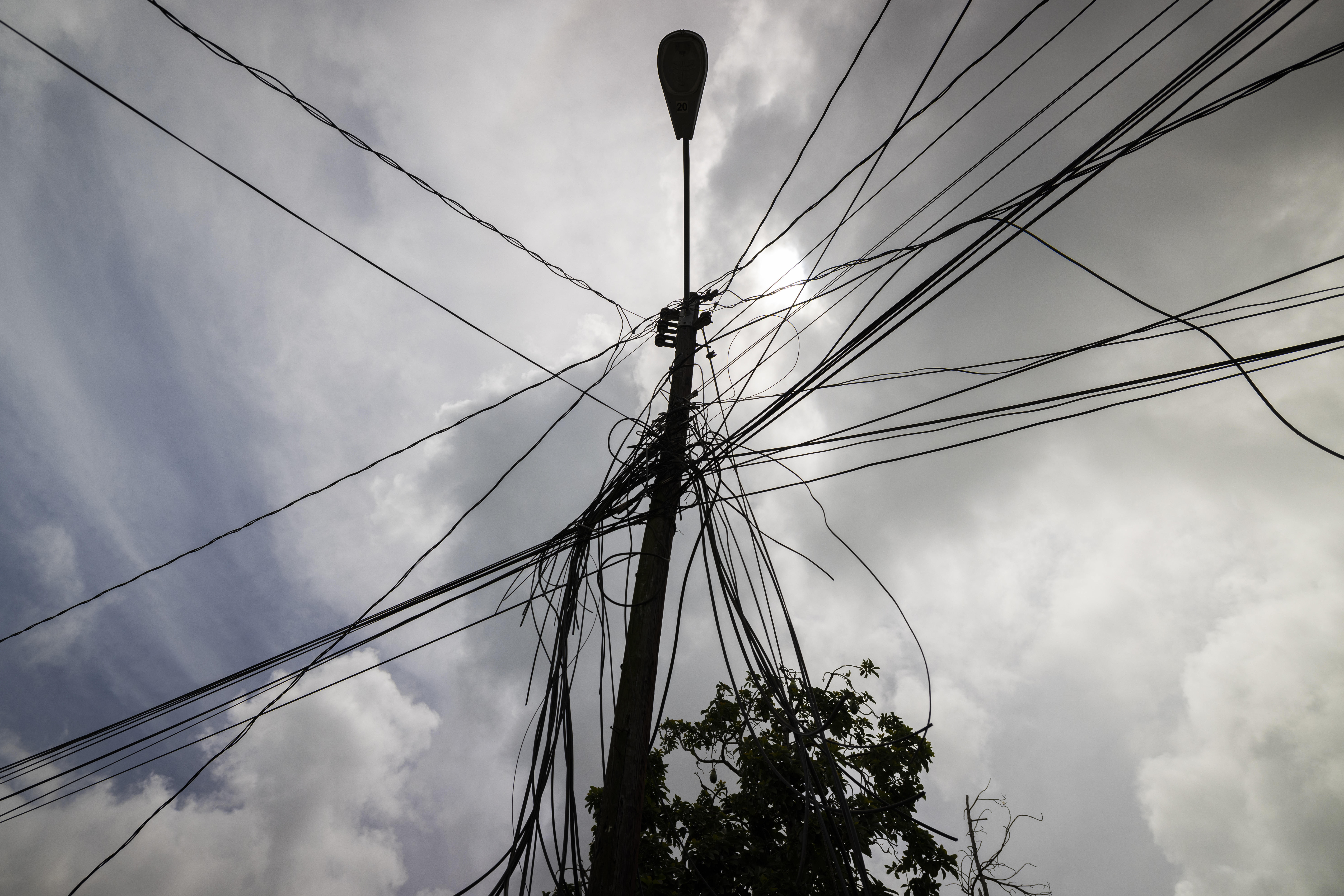 A utility pole with loose cables towers over a home in Loiza, Puerto Rico, Sept. 15, 2022.