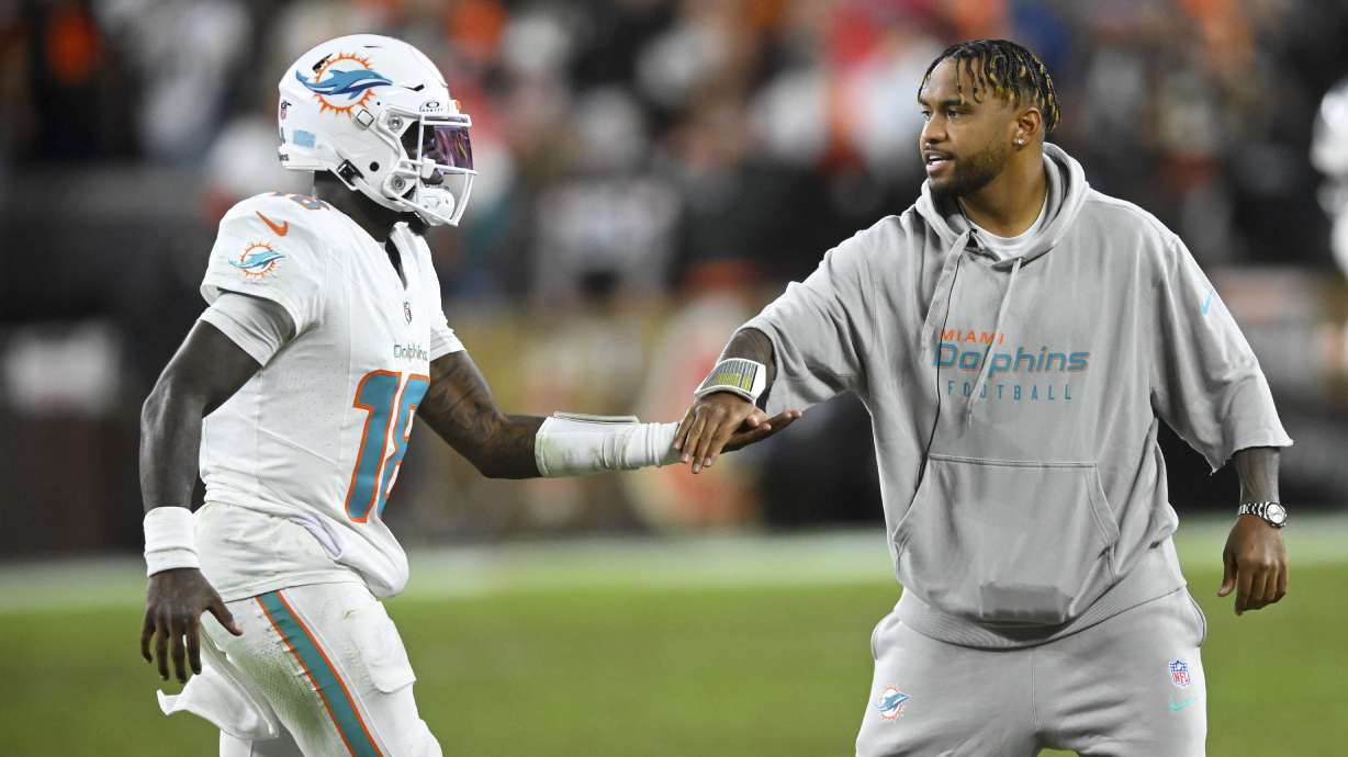 Miami Dolphins quarterback Tua Tagovailoa, right, greets quarterback Tyler Huntley (18) as he comes off the field during the first half of an NFL football game against the Cleveland Browns Sunday, Dec. 29, 2024, in Cleveland.