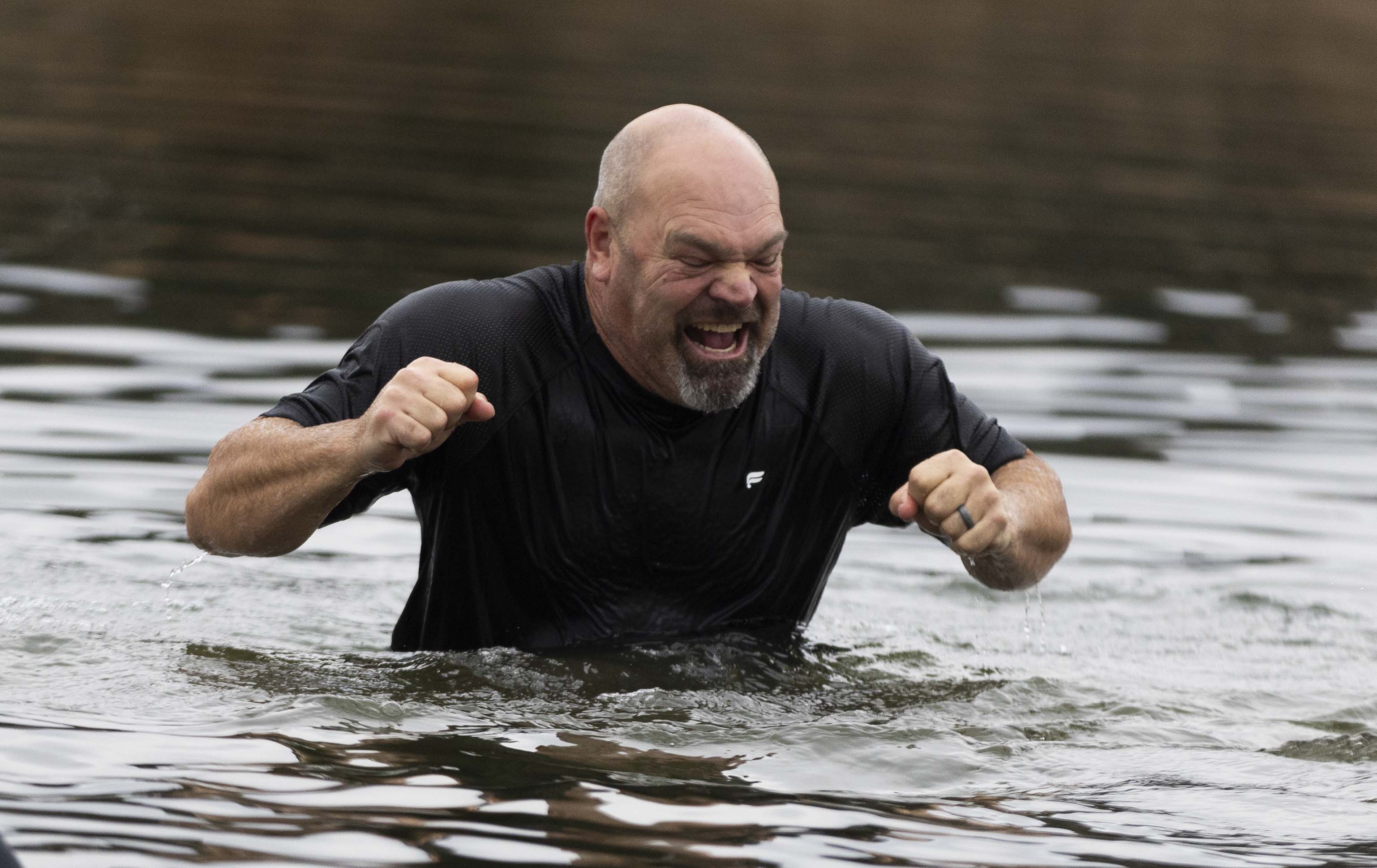 Mark Baker, from Salem, cringes as he reacts to the cold water and decides to immediately get out of the water during the 10th annual Pond Town Polar Plunge in Salem on Wednesday, New Year's Day 2025.