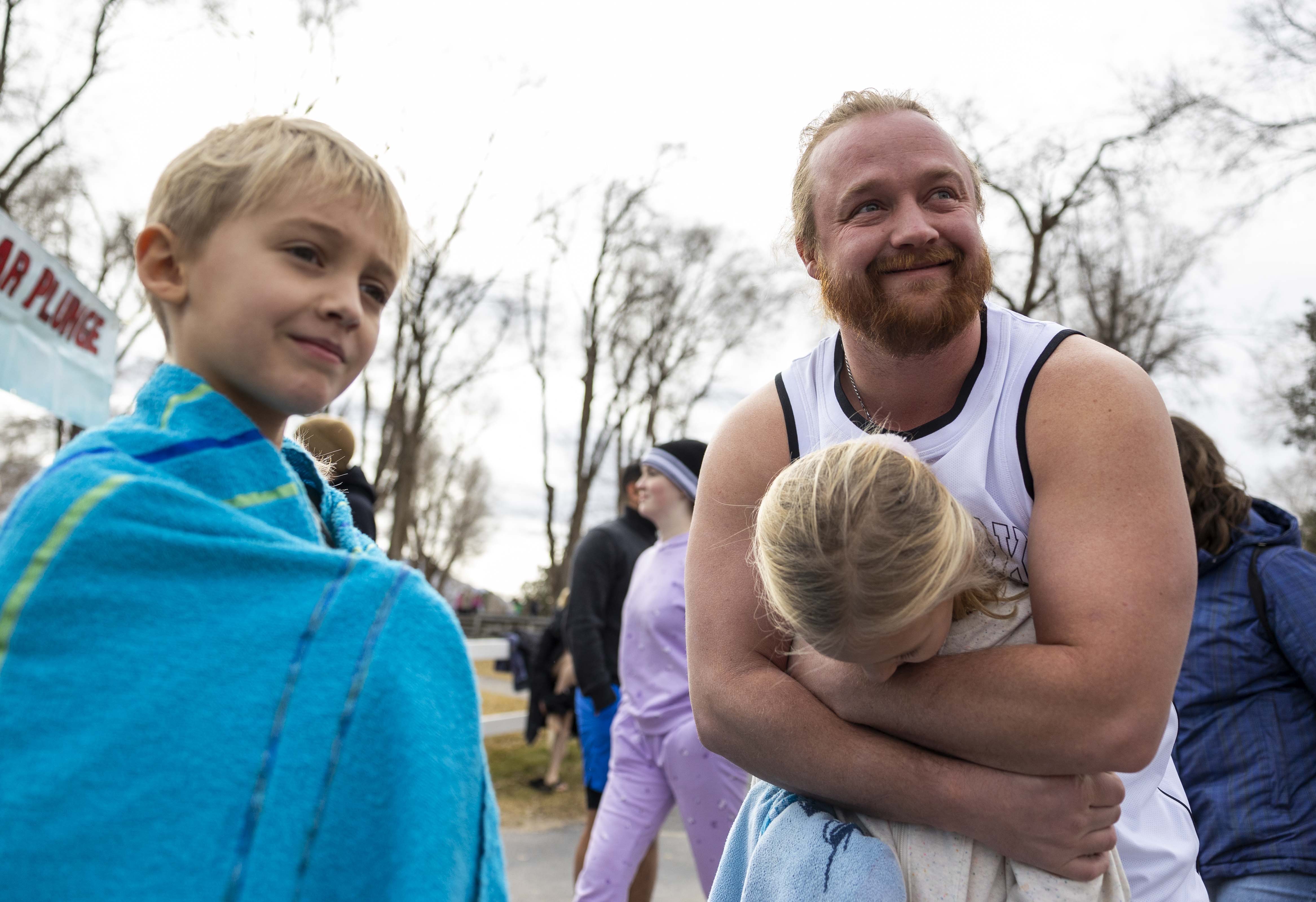 Justin Olsen, right, holds his daughter Kara, 10, to keep her warm while they wait with her brother Jason Olsen, 8, for the start of the 10th annual Pond Town Polar Plunge in Salem on Wednesday.