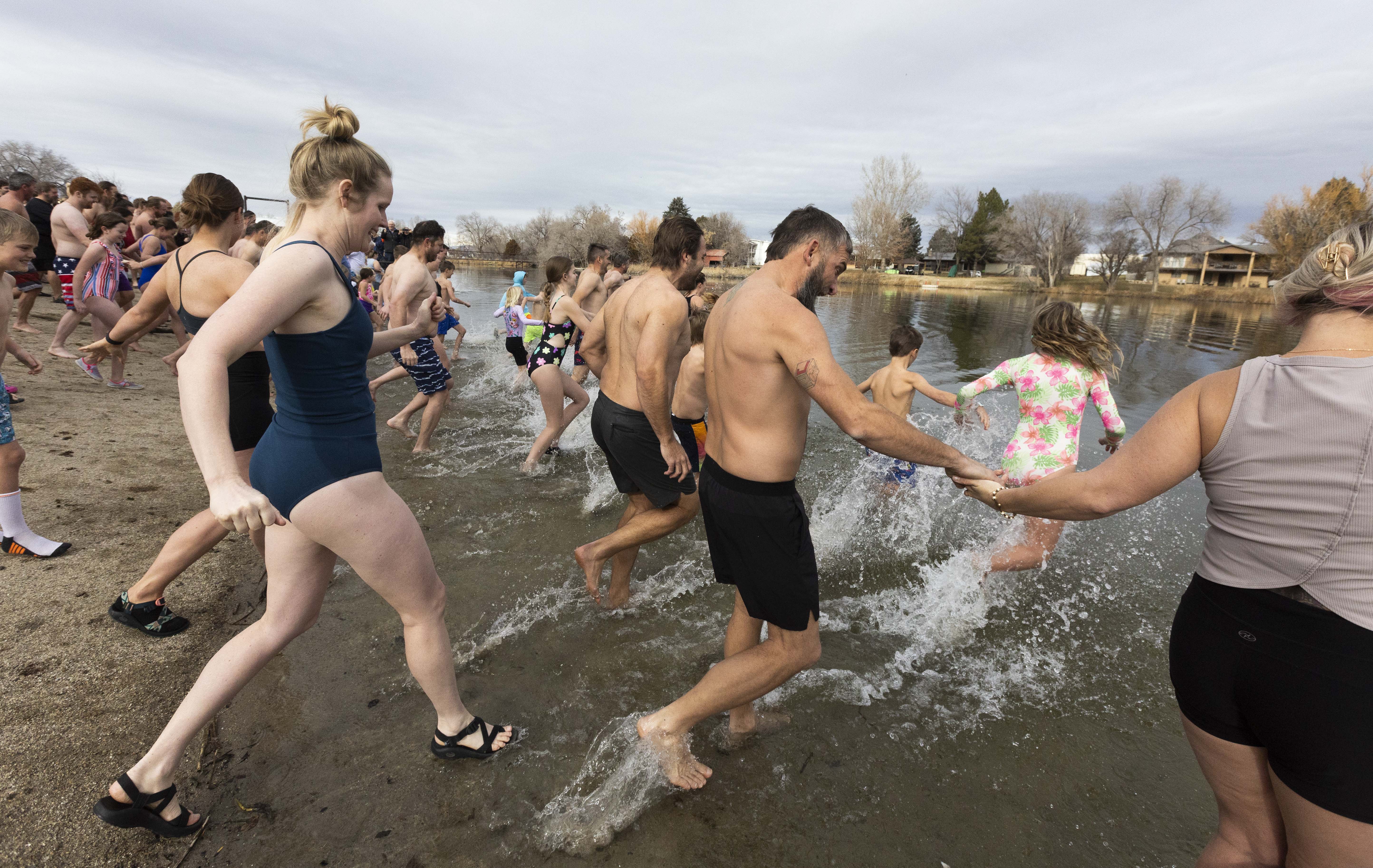 People rush into the cold water at the 10th annual Pond Town Polar Plunge in Salem on Wednesday, New Year's Day 2025.